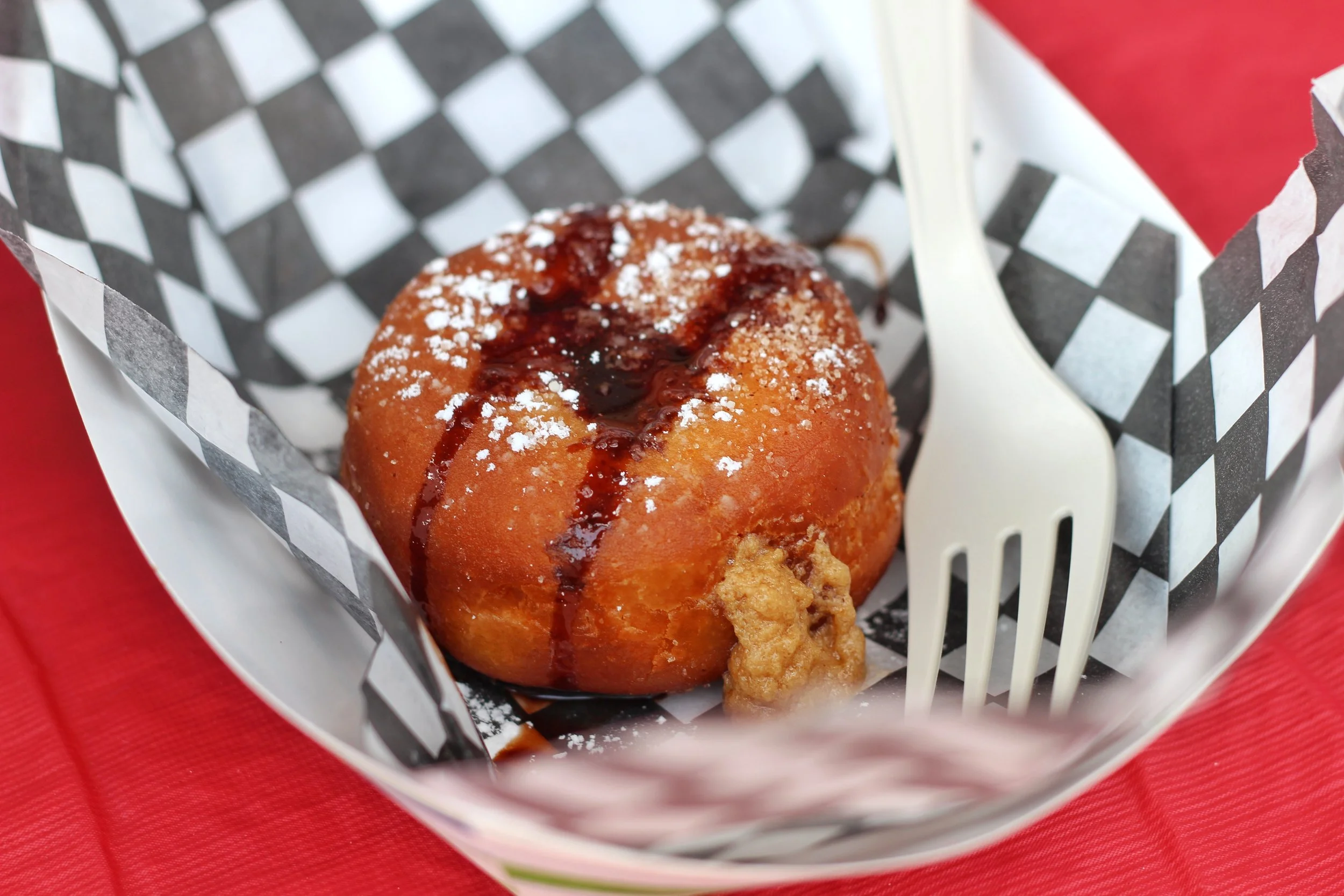 Deep fried sweet dough stuffed with a peanut butter Sriracha filling, dusted with cinnamon icing sugar and drizzled with chocolate syrup.