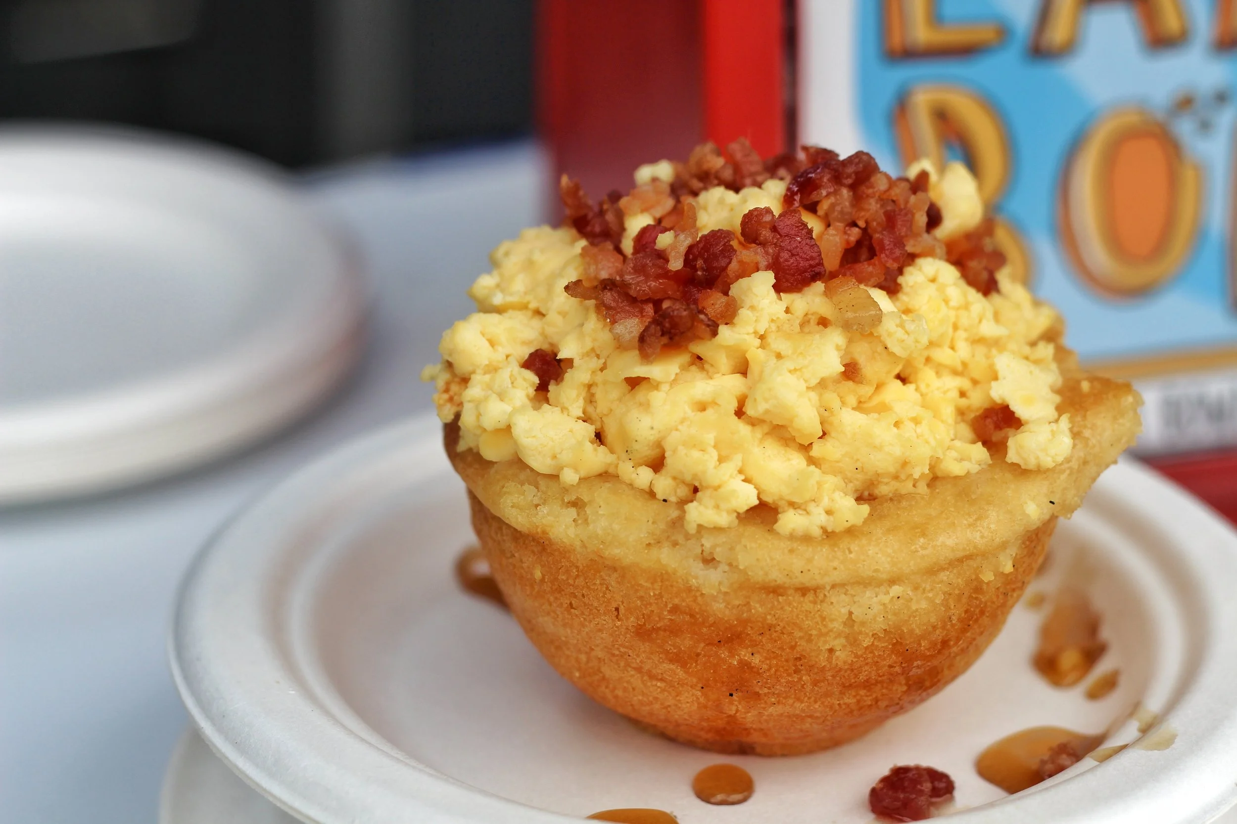 A pancake breakfast bowl with scrambled eggs and maple syrup.