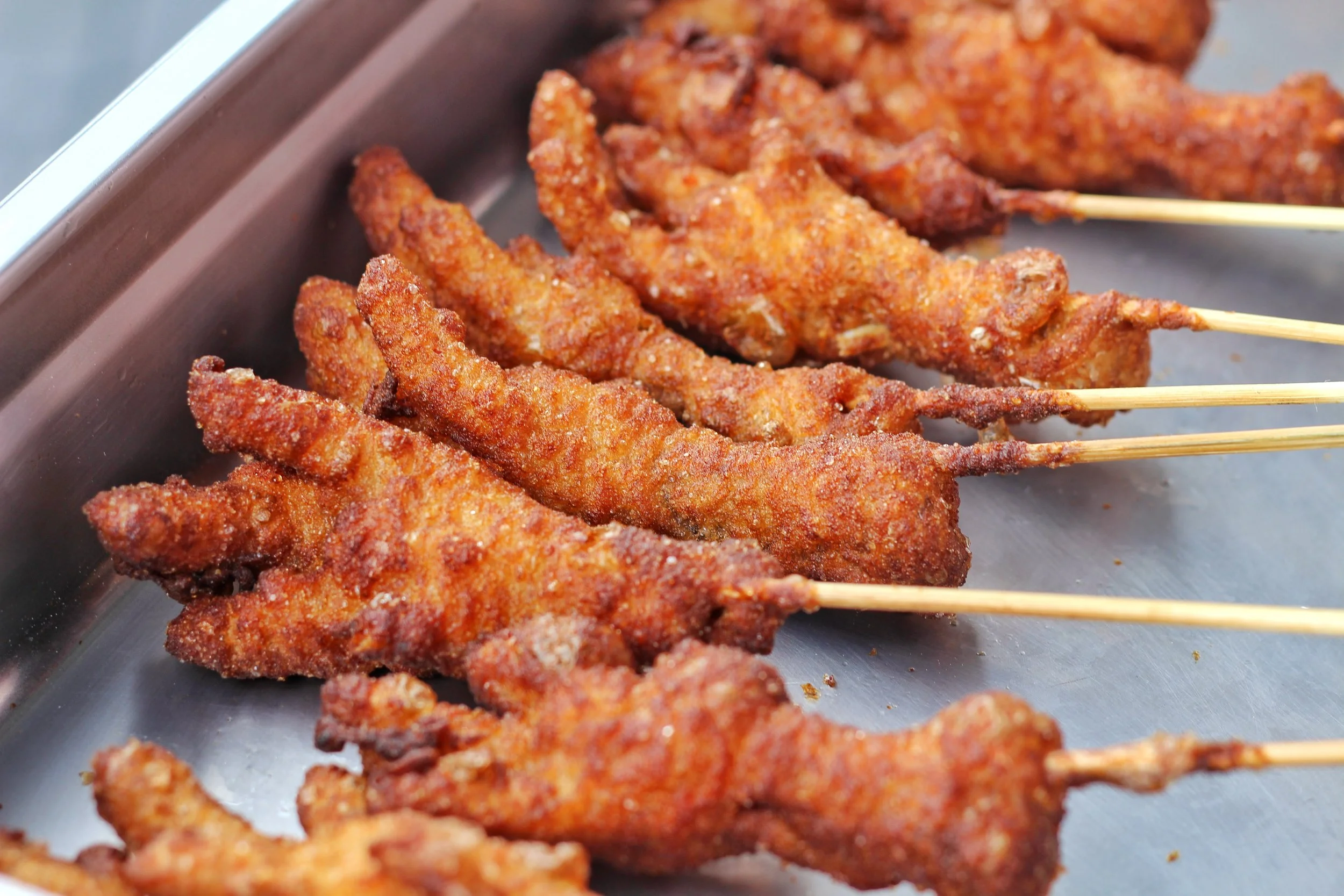 Crispy chicken feet served on a stick.