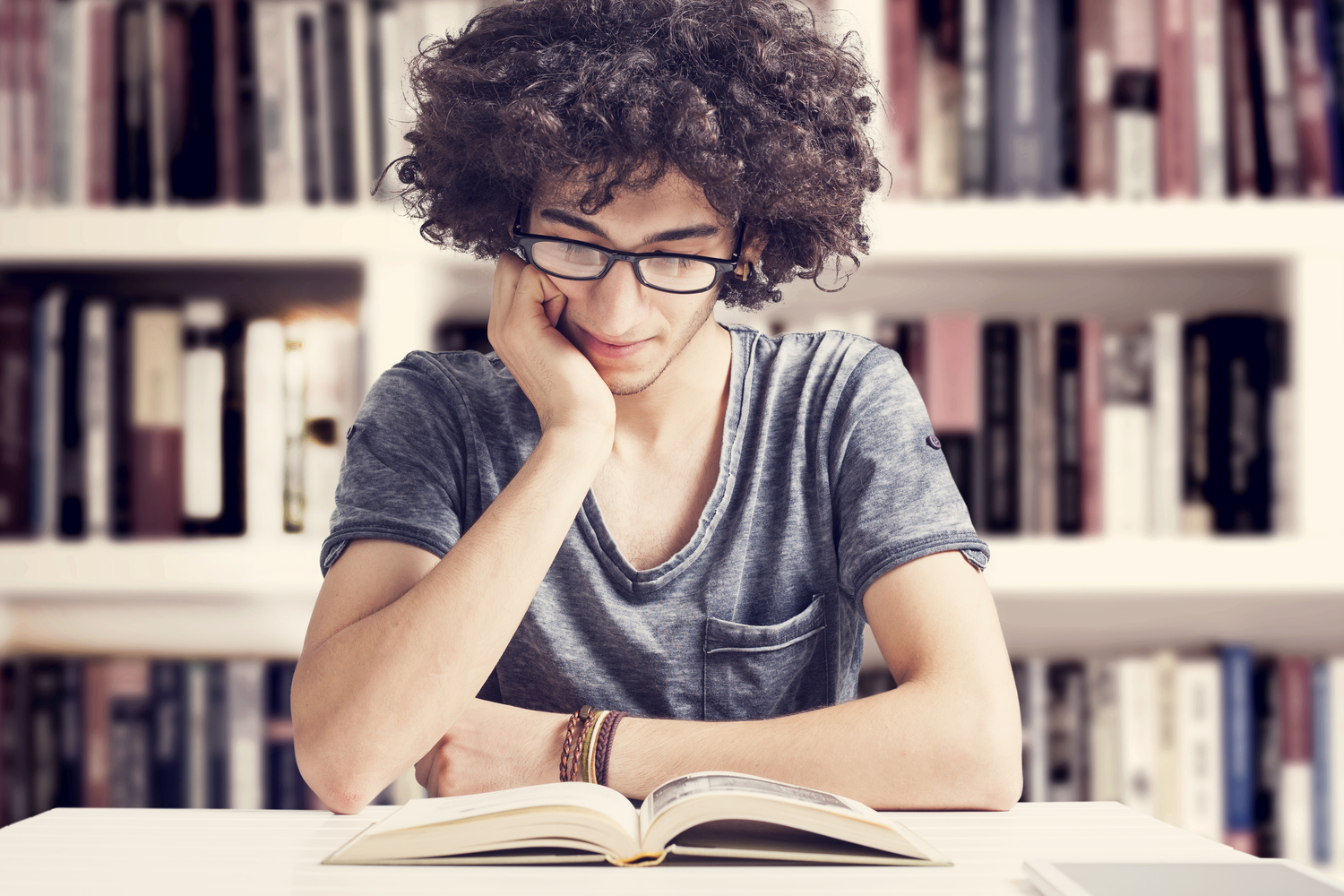 Young student reading book in library