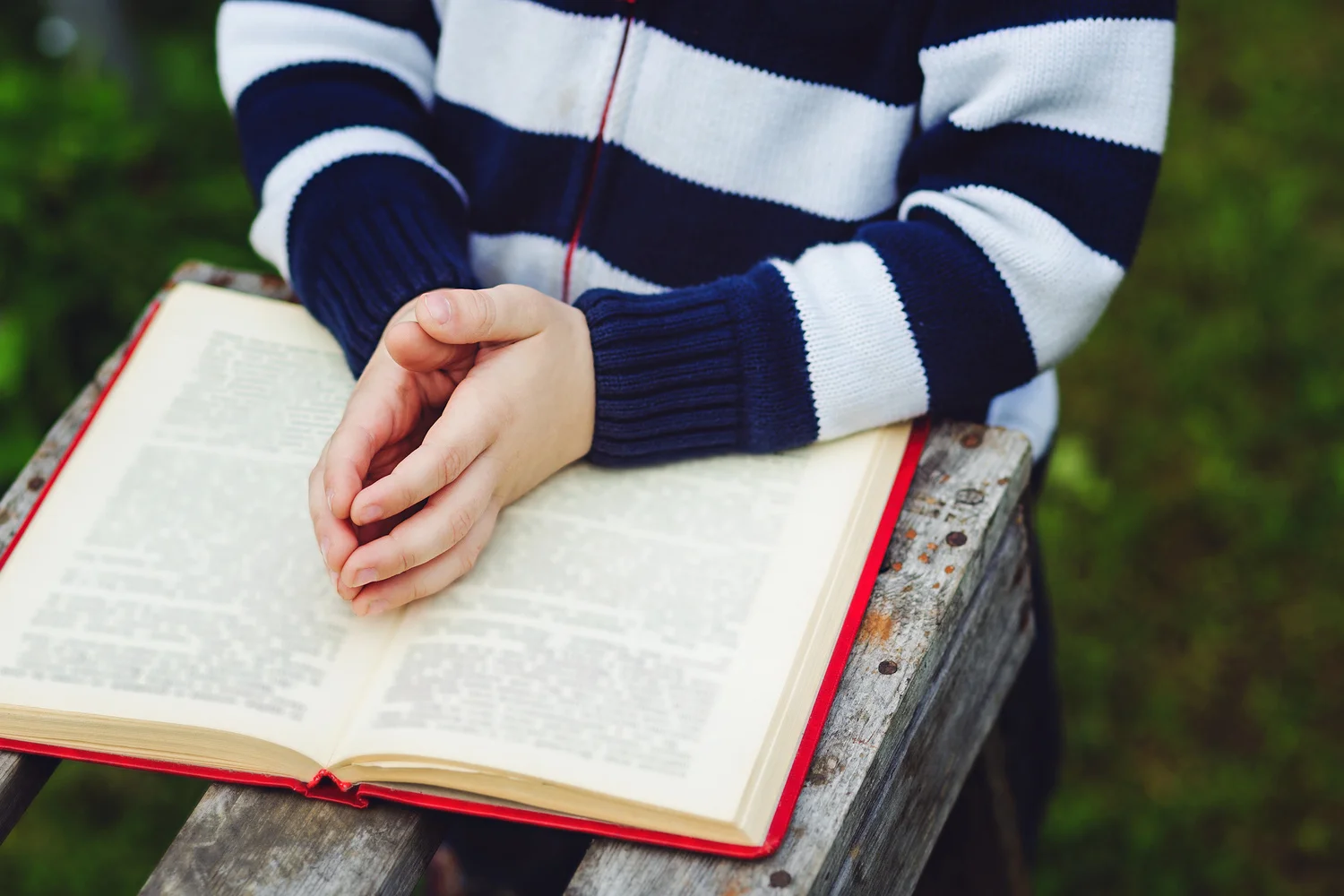 Child hands are on folded in prayer on a Holy Bible. Concept for