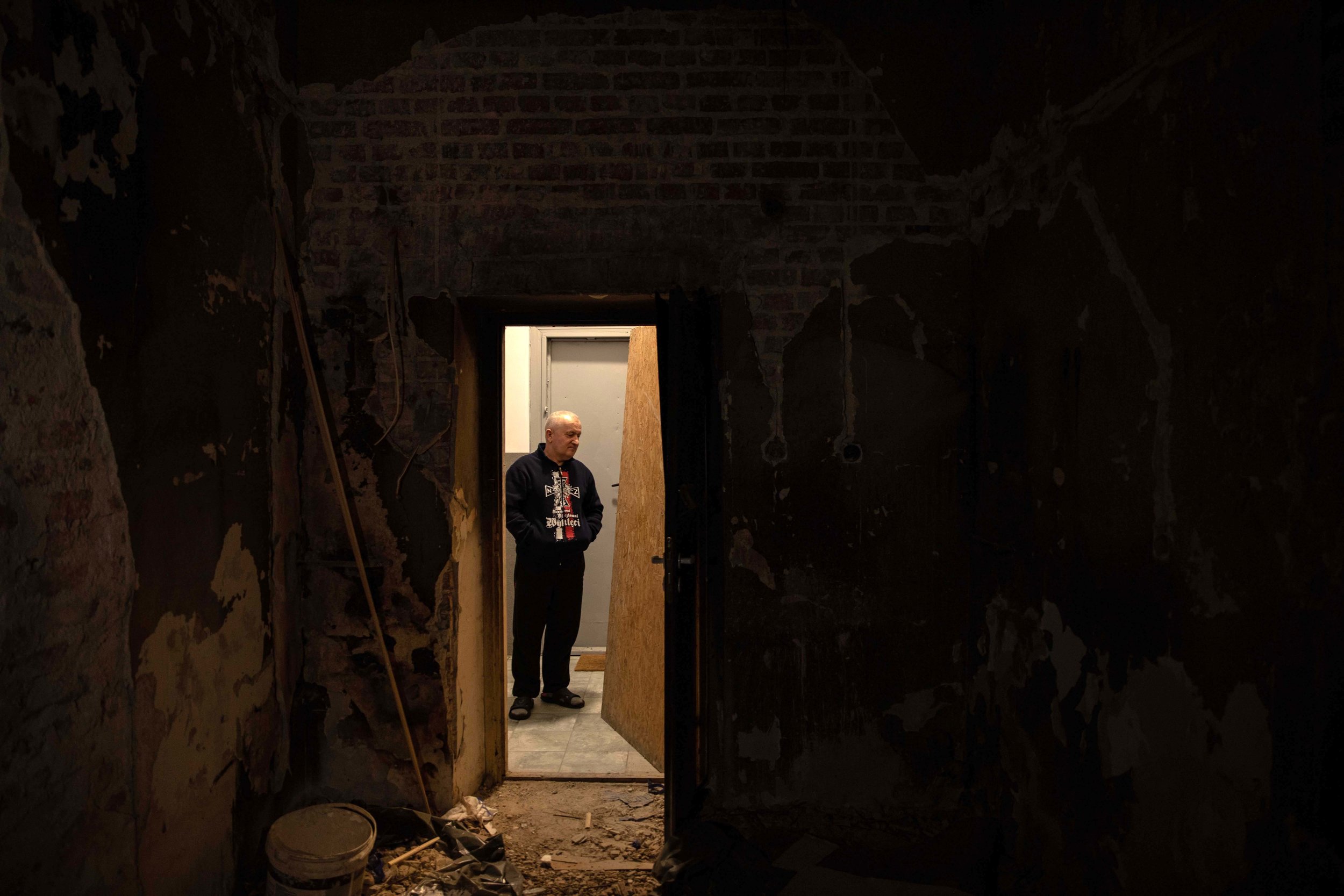 WARSAW • Stanislaw, a friend, stands in the hall of the flat Ryszard Kowalski moved into in the 1970s with his wife and her parents. Forty years on, nothing has been done to improve the building.