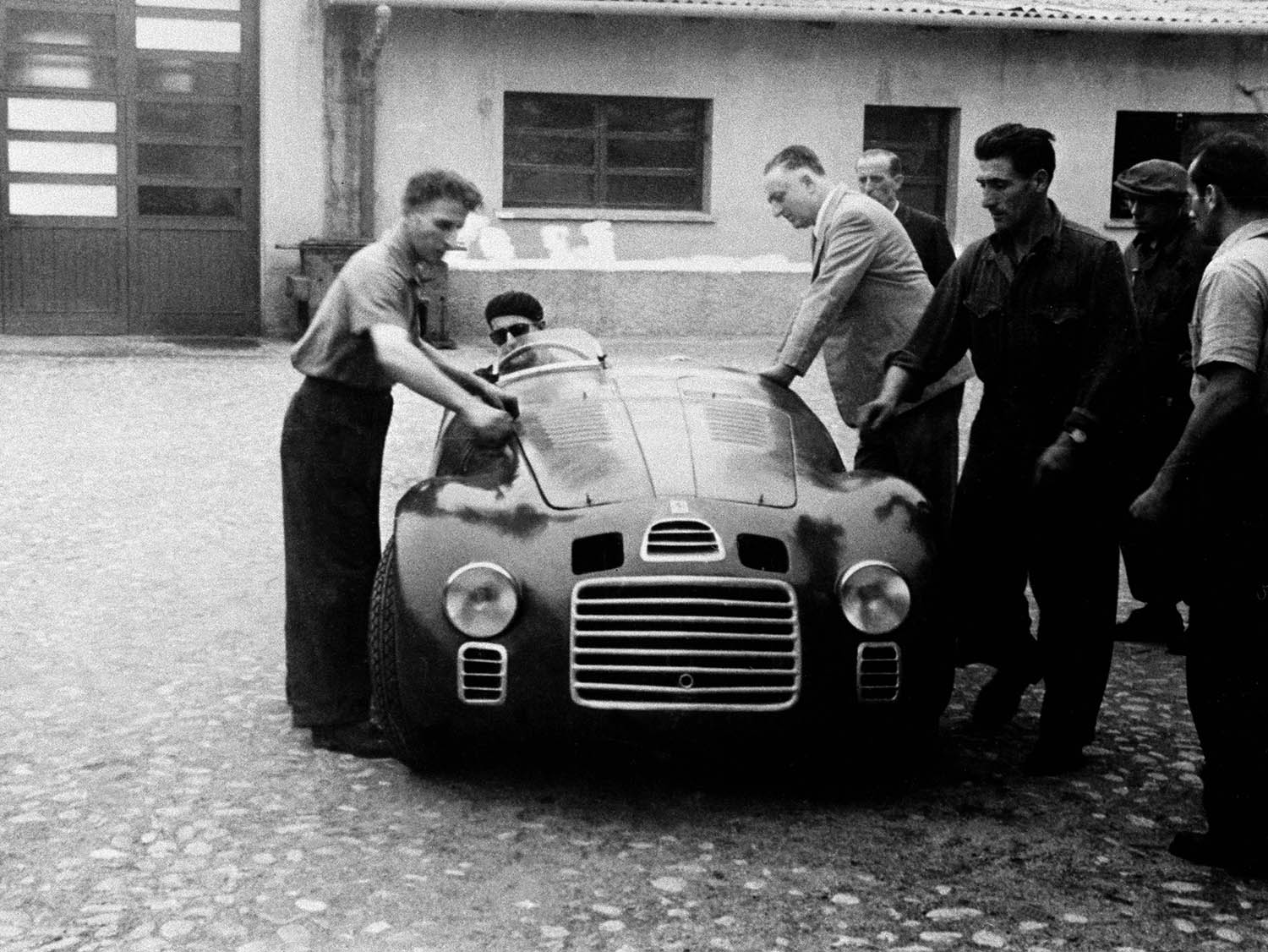 2. Enzo Ferrari with the 125 S in the courtyard of Fabbrica. At the wheel is Ferdinando Nando Righetti.jpg