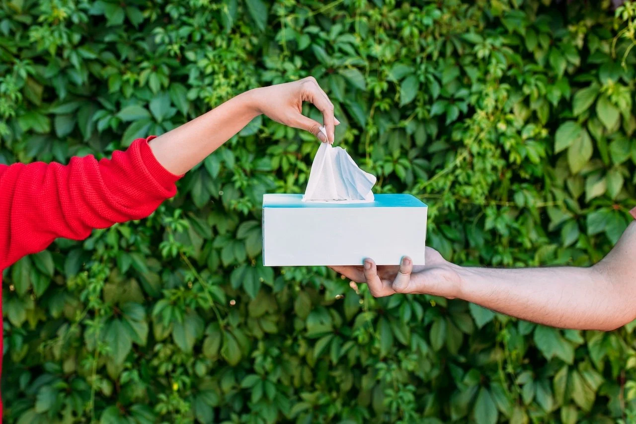Hand pulling tissue out of box, outdoors
