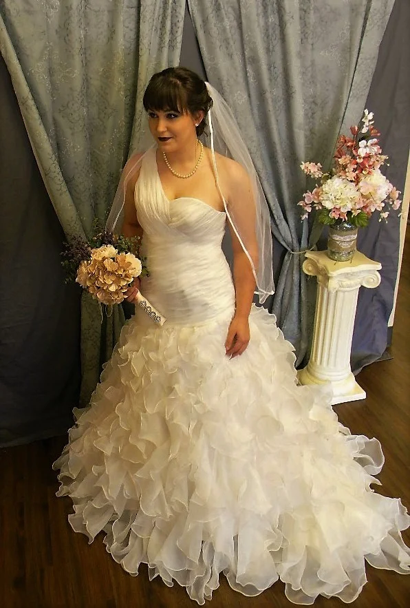  One shouldered mermaid with ruffles, ruffles, ruffles! &nbsp;Spectacular dress available in sizes up to 28. When choosing a veil for a gown like this, you don't want it compete with the dress. There are a few options, a simple tulle veil with a sati