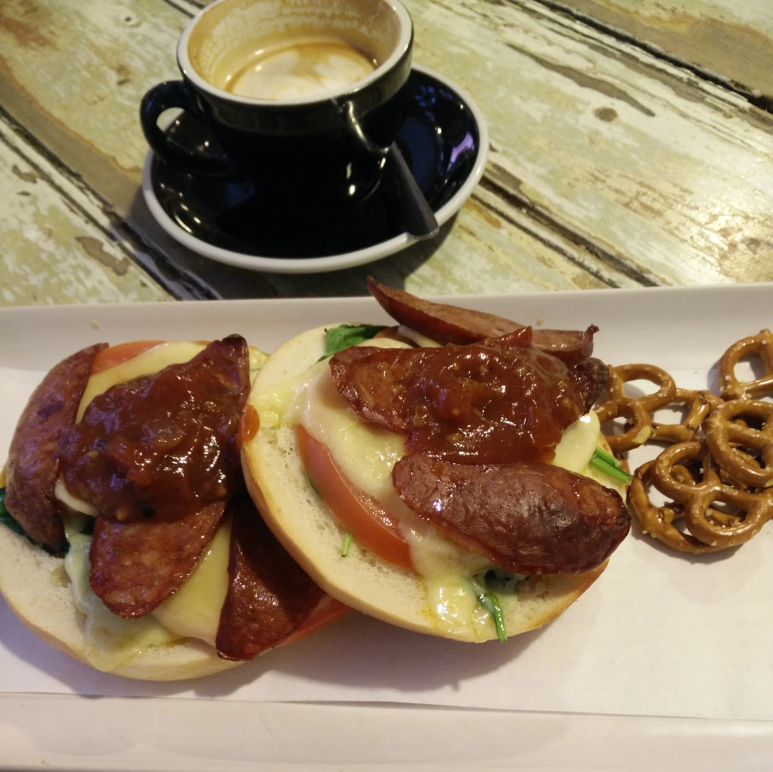 Open-faced chorizo bagel sandwich with a flat white.