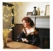 The author in her living room, dressed in a dark green gown, probably a costume from an opera.