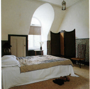 A guest bedroom under the eaves, with a curvaceous Aesthetic Movement screen stretched with roughly hand-woven silk.