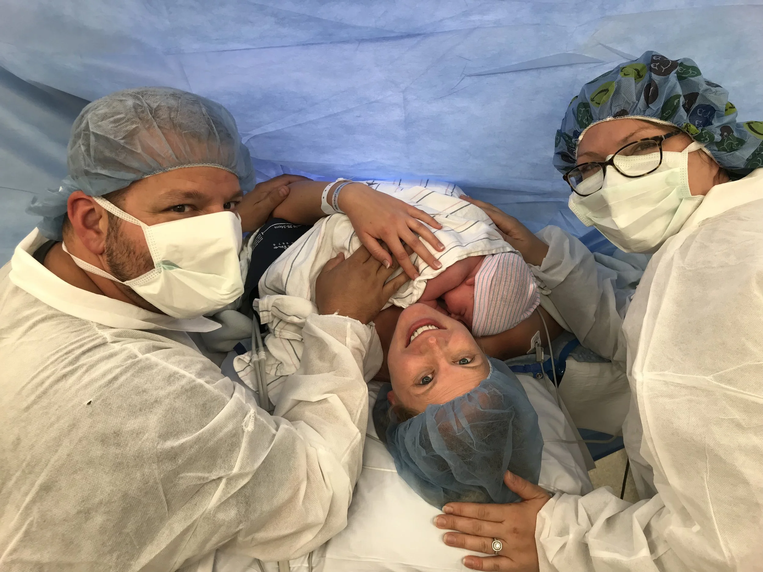 Doula Jen, right, with brand new baby K and his mom and dad after a provider supported “ family centered” cesarean birth in the Twin Cities, MN.