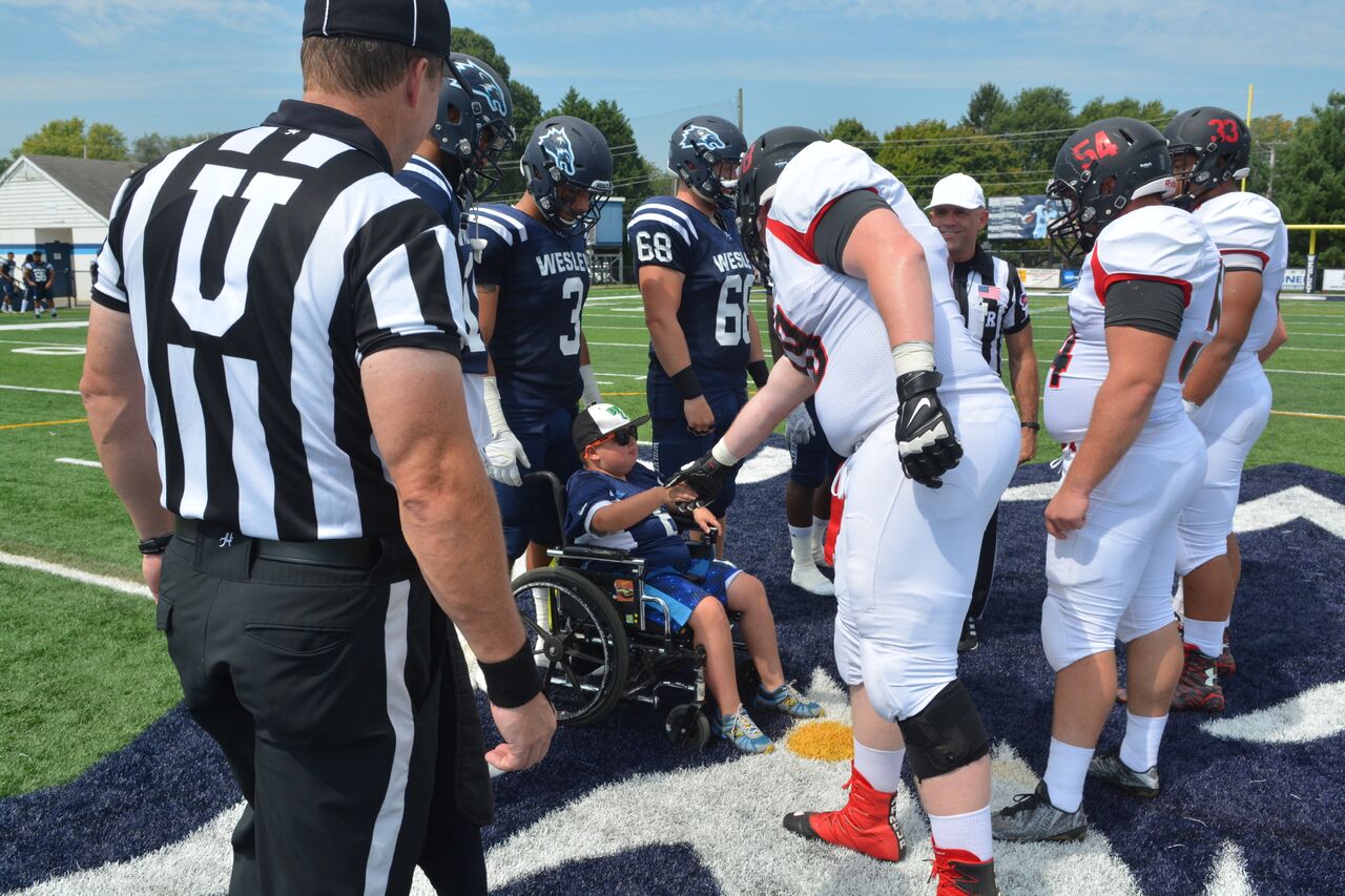 DMD Muscle Champion, Eddie Hazeldine, and the Wesley Football Captains shake hands with Frostburg State to begin the coin toss. Photo courtesy of Wesley College Athletics. Copyright 2016, Wesley College Athletics
