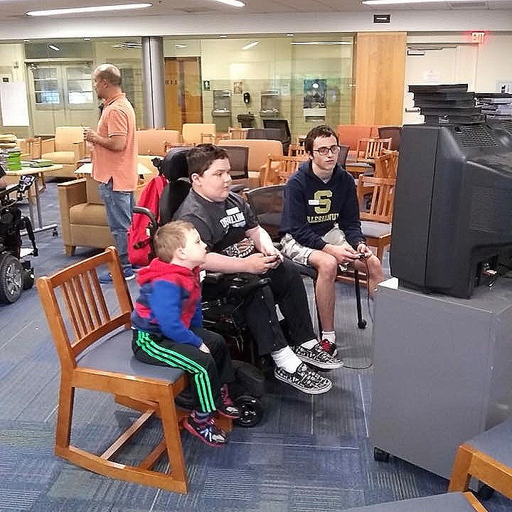 MMF Muscle Champions, Josh and Colty Wallace, enjoy a video game with a student from Salesianum School