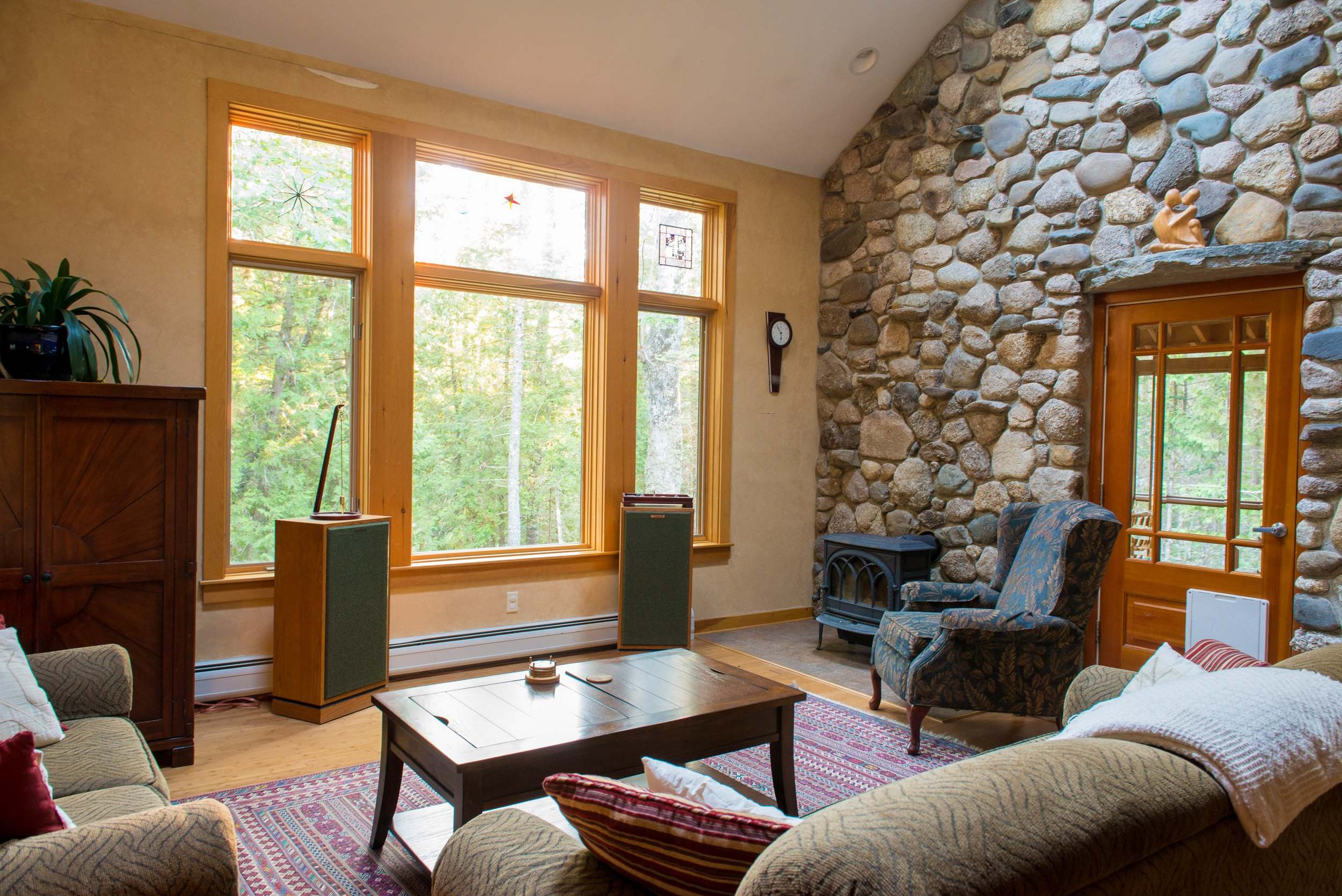  Living room with ample seating, two story native stone wall and porch door. 