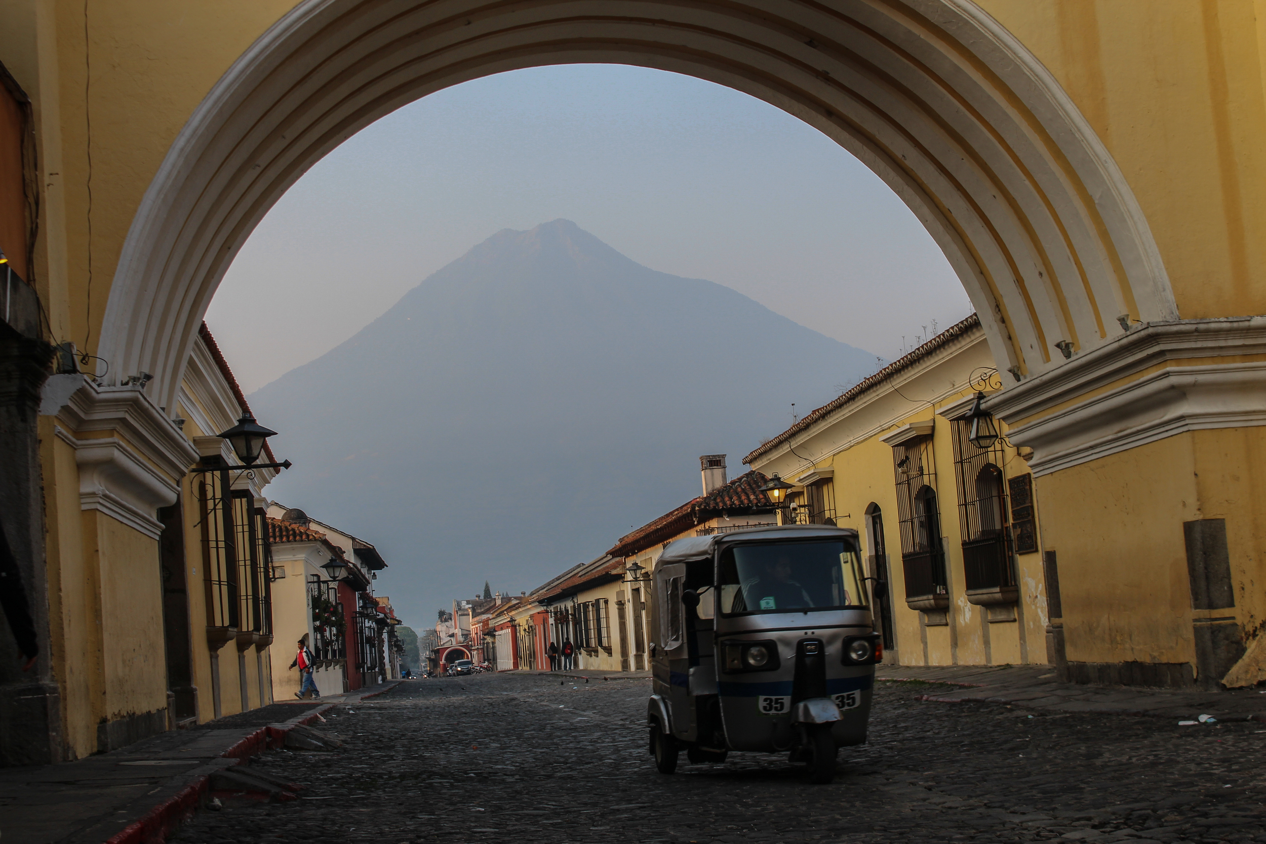 A tuc-tuc, Antigua's arch and Agua Volcano looming in the background
