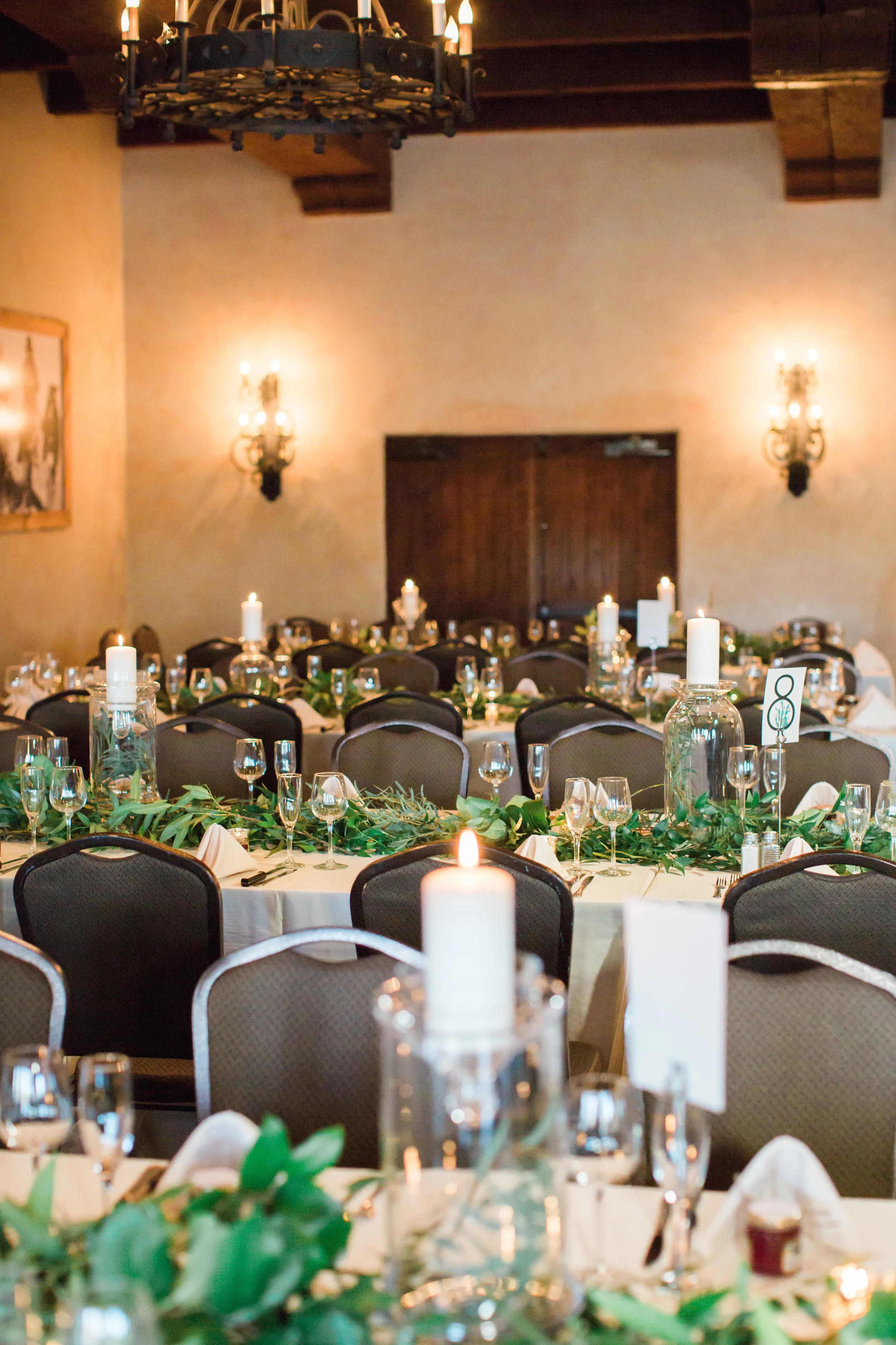Elegant green and white wedding reception set up covered in candles