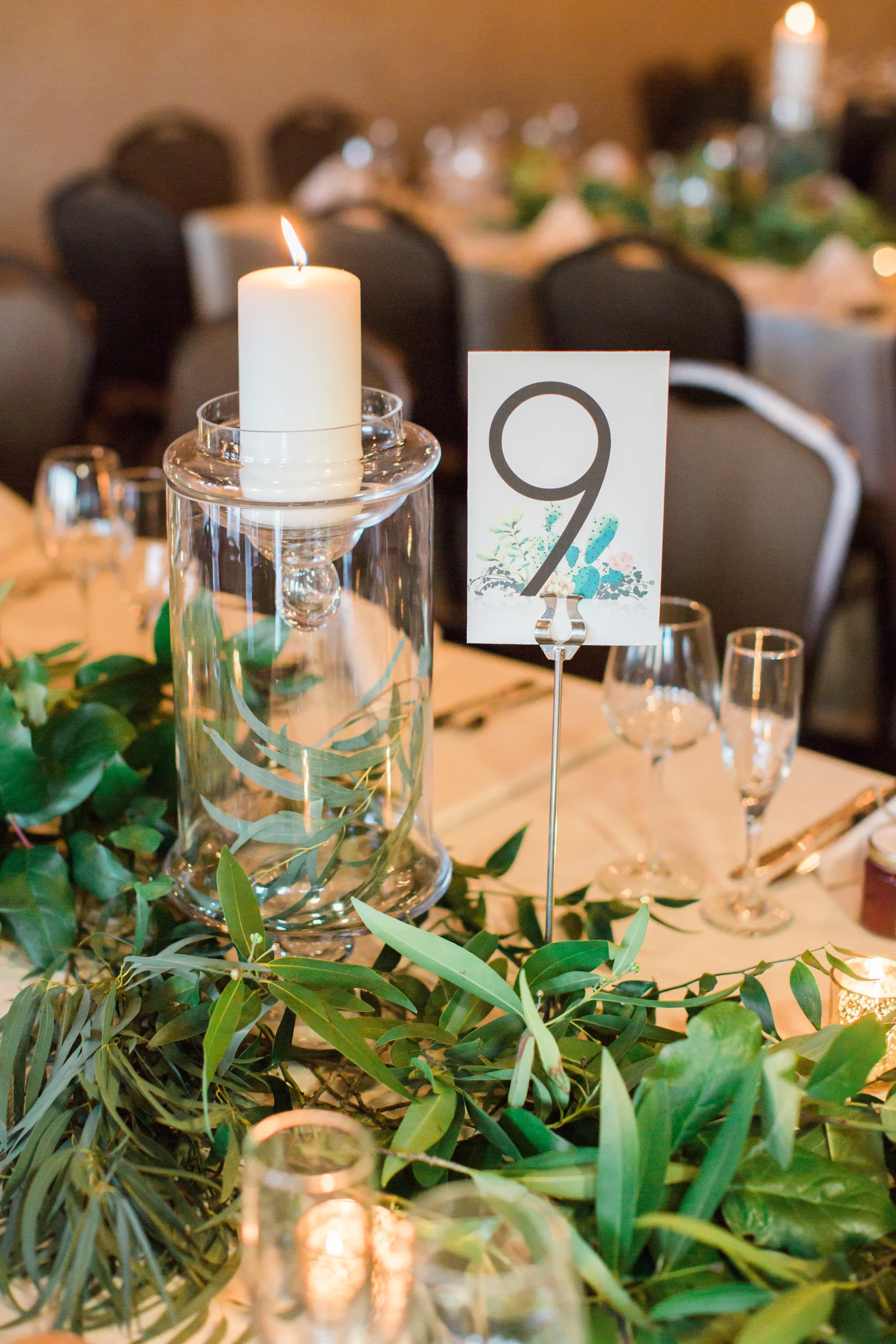 Tables draped in greenery and covered in candles. Table numbers designed by Gorgeous place cards design by briedumaisdesigns.com