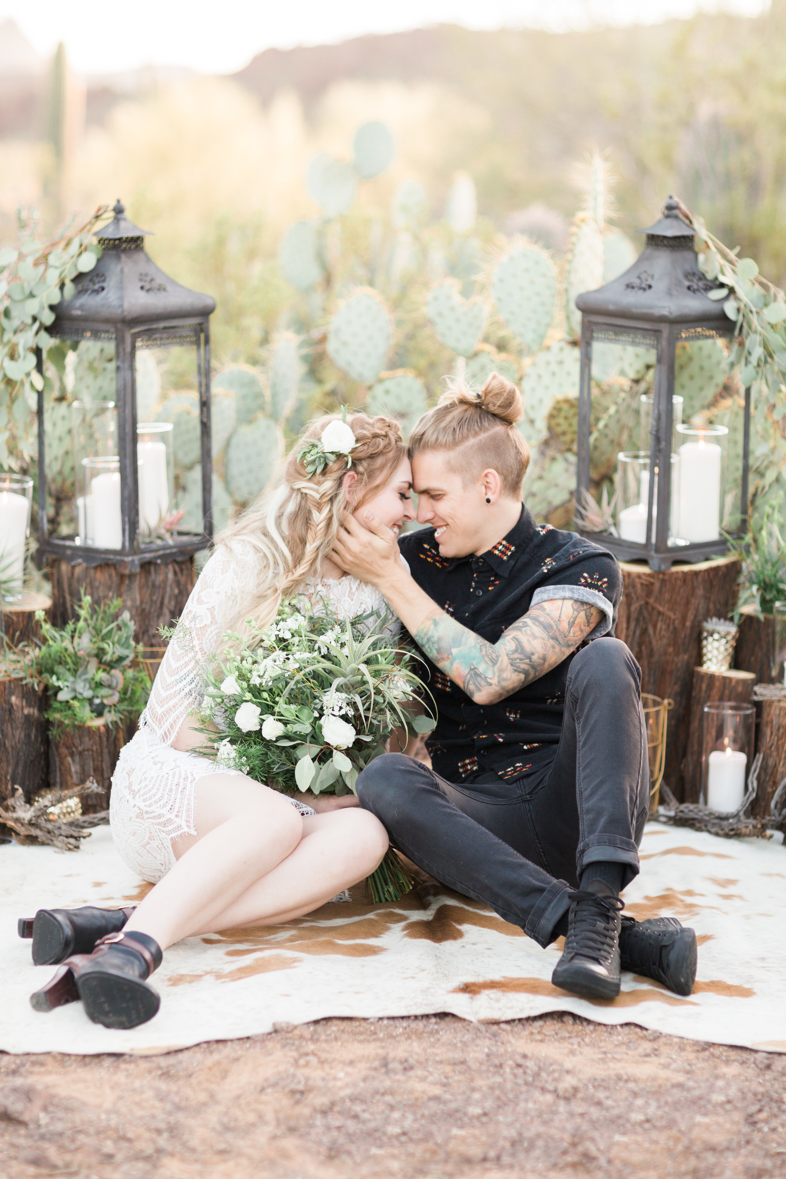 Groom cuddling with bride sitting down in the desert