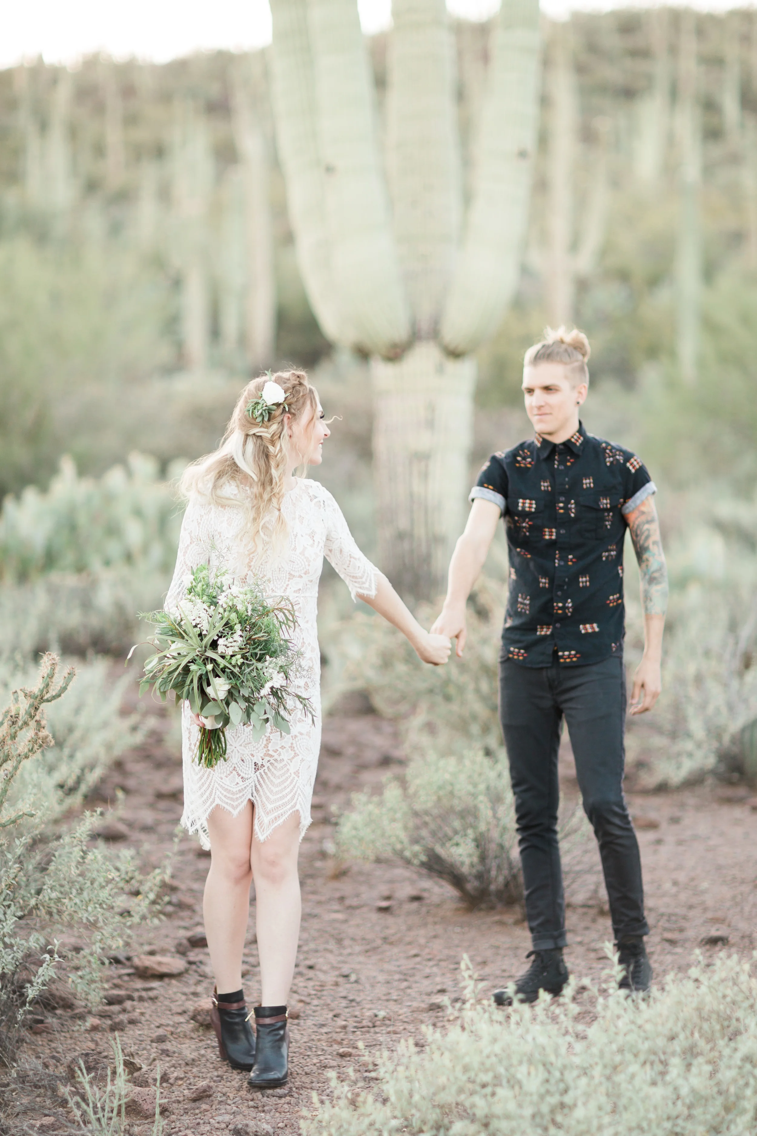 Bride and groom holding hands with huge saguaro in the background
