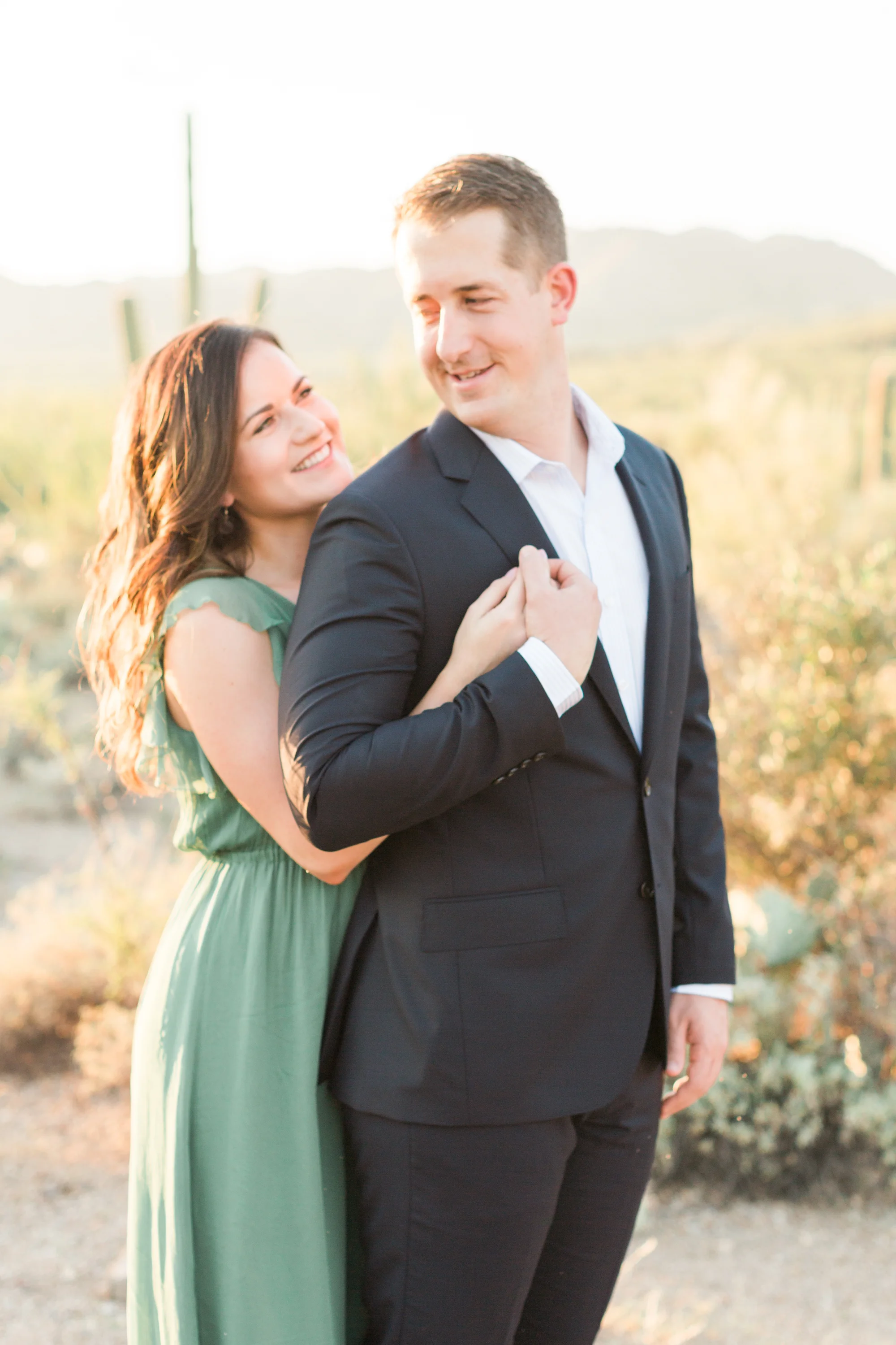 Gorgeous couple hugging at their engagement session in Tucson, AZ with the golden hour desert in the background. 