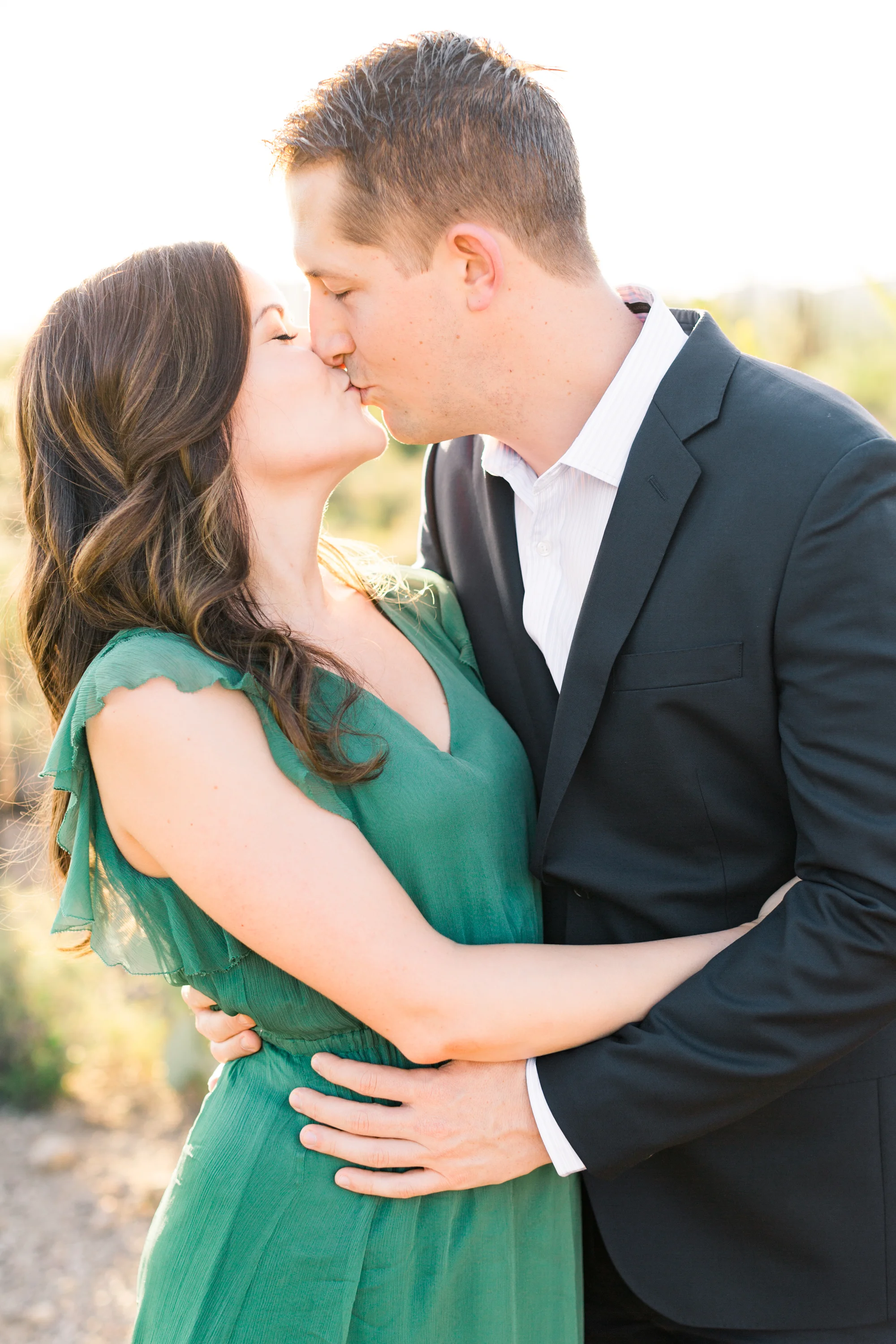 Couple kissing at their engagement session with the golden hour desert in the background. So cute! 