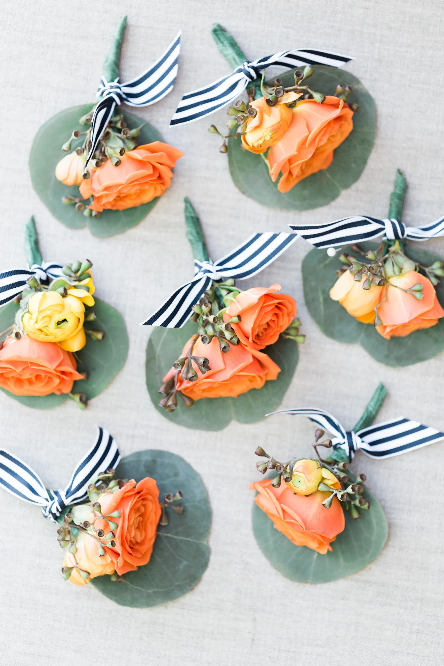 Orange and salmon rose boutonnieres with striped navy and white ribbon. So dreamy! 