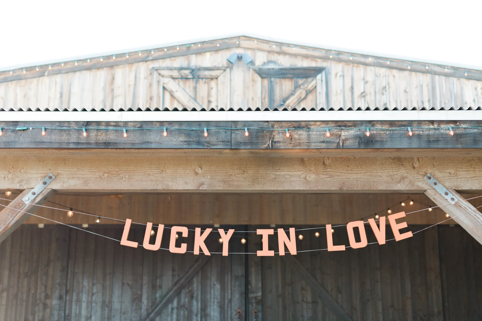 Lucky in love sign hanging from the top of the barn, where the cocktail hour will take place.