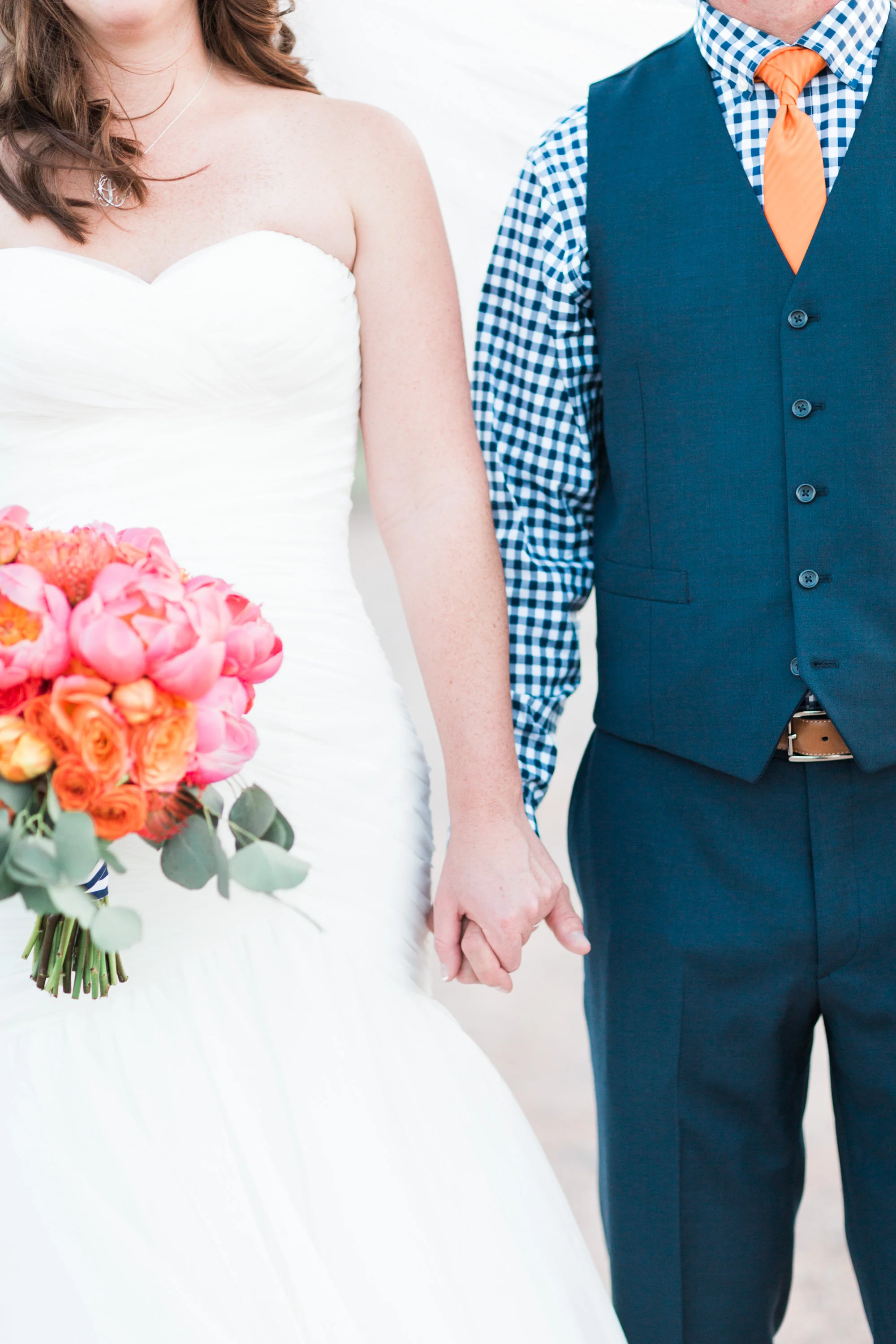 Bride and groom holding hands, standing side by side.