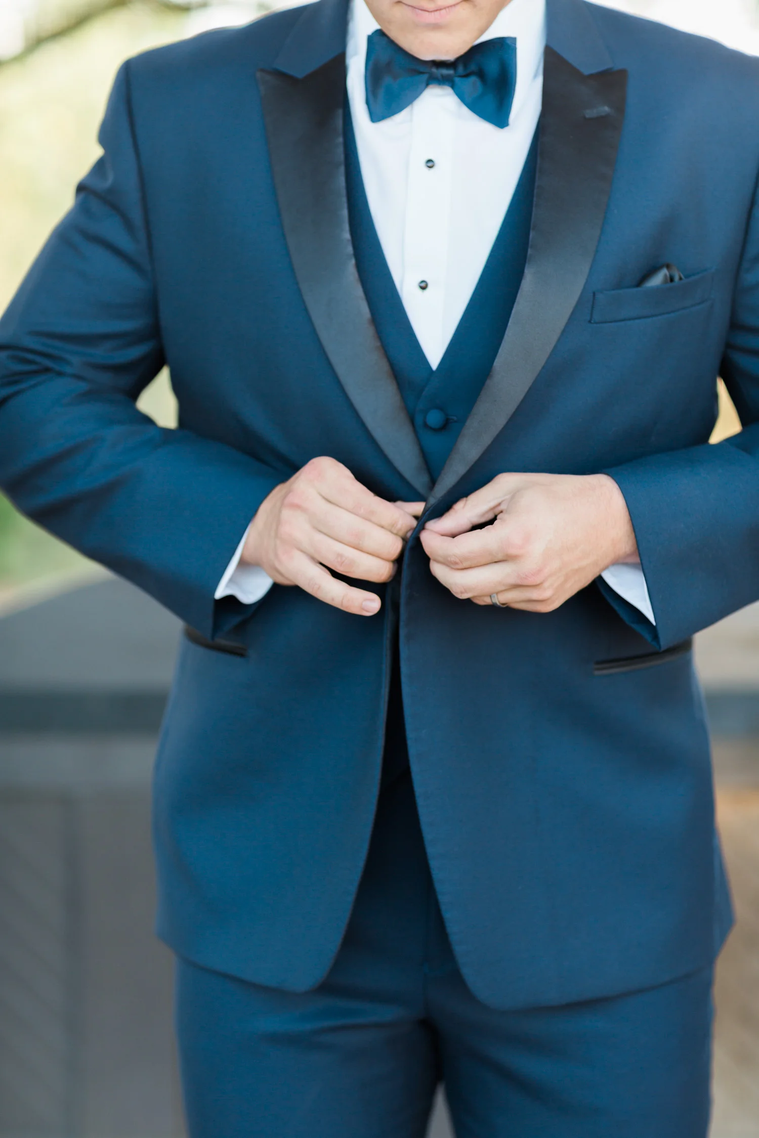 Groom in navy, buttoning hus tuxedo jacket