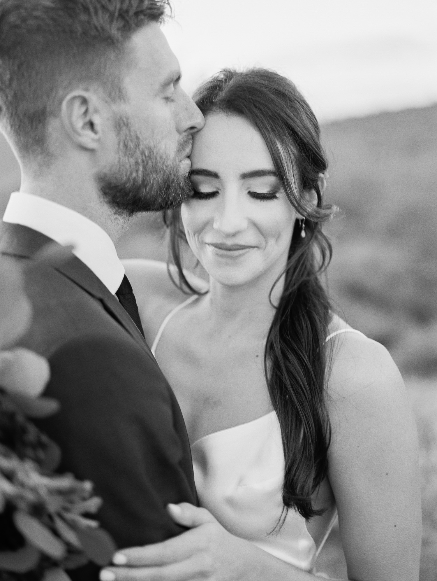 Such a sweet photo of groom kissing his new bride on the forehead at their Phoenix elopement.