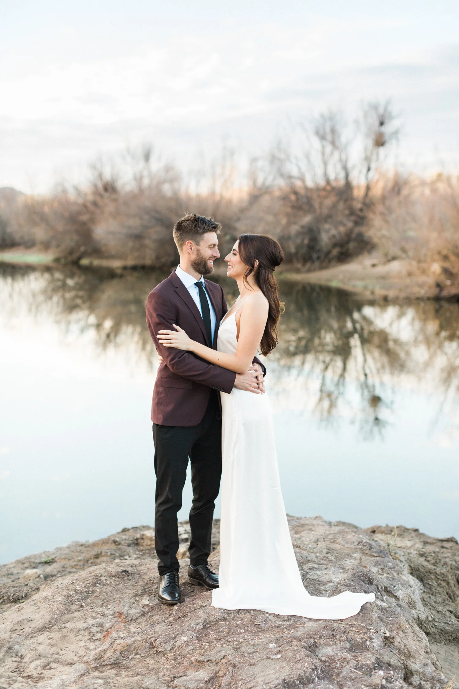 Beautiful bride and groom embracing at their Phoenix elopement with the Salt River in the background.