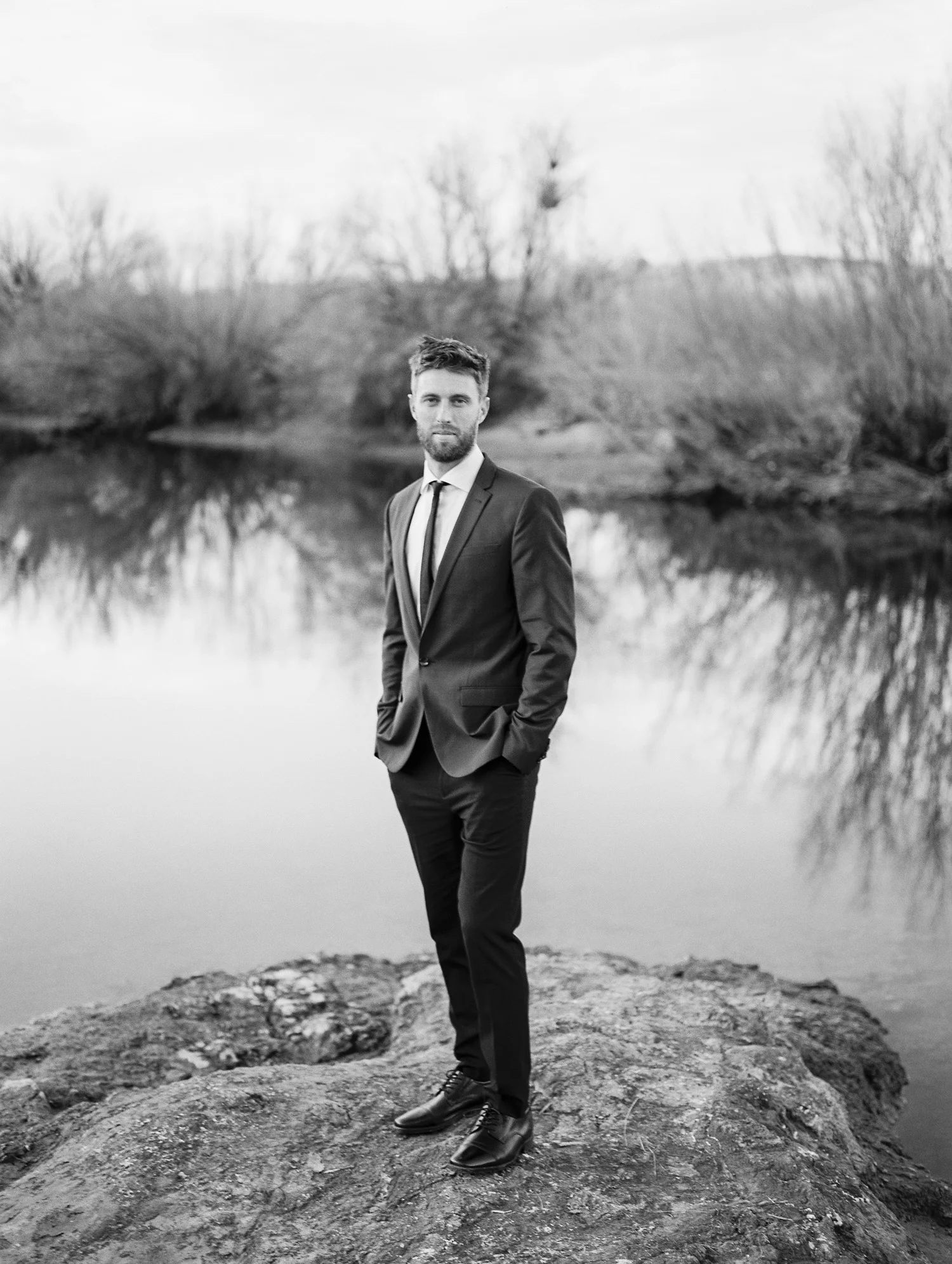 Black and white film photo of groom along the Salt River in Phoenix, AZ.