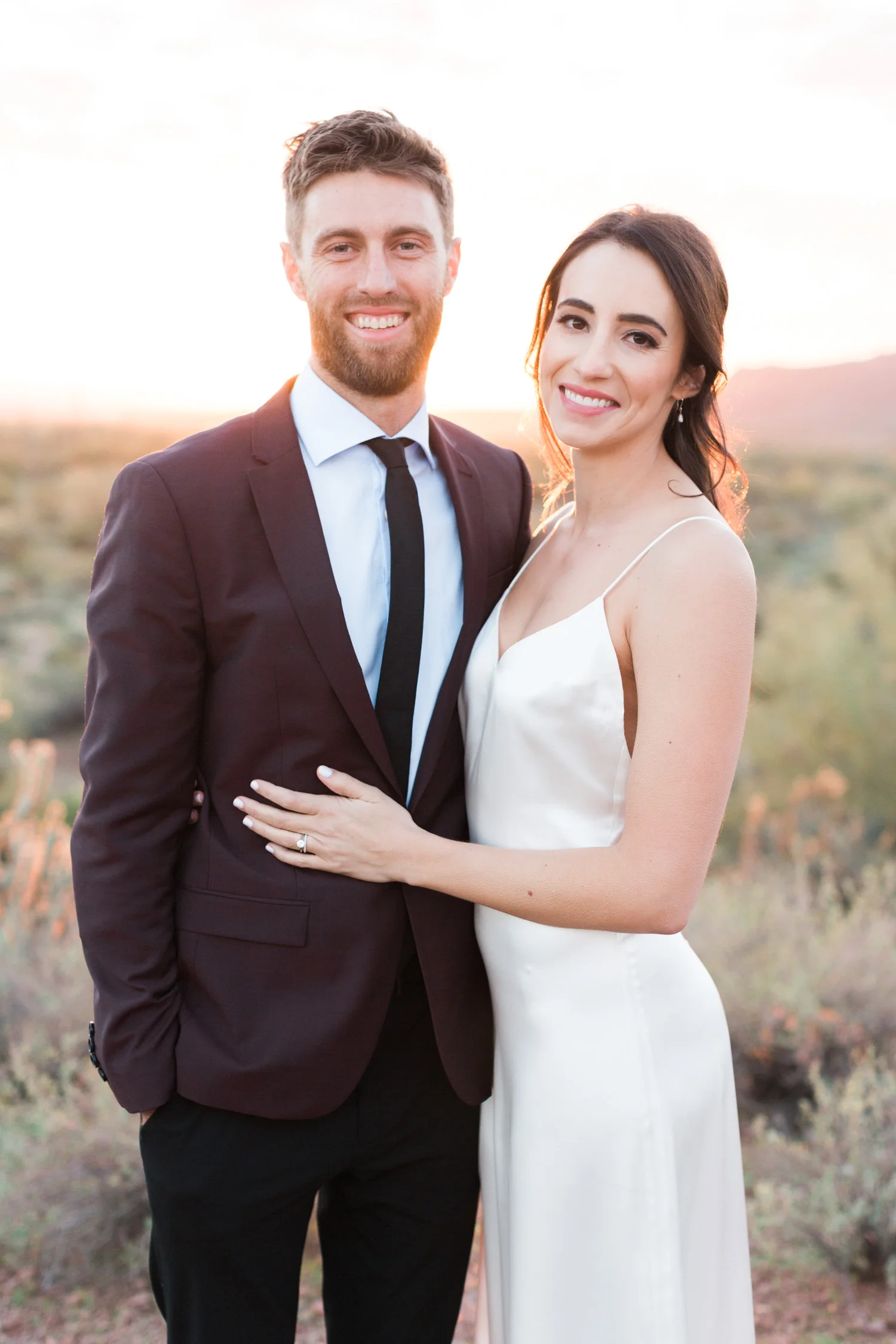 Bride and groom smiling at the camera with a gorgeous Phoenix sunset on their wedding day! 