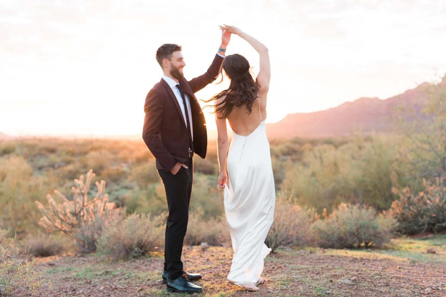 Groom twirling his bride in the desert on their wedding day.
