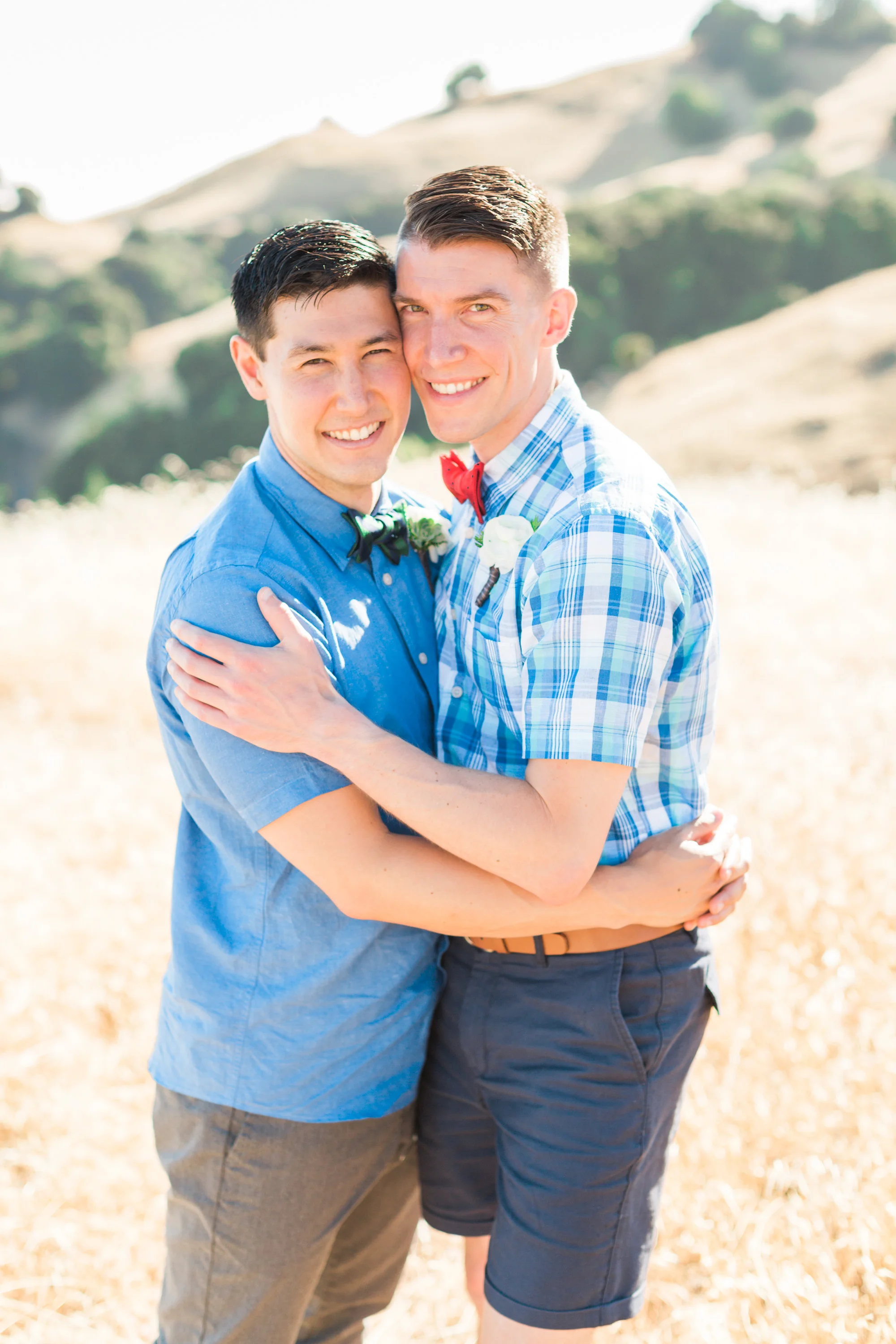Grooms hugging on their wedding day at the top of Mount Tamalpais, with gorgeous golden hills in the background.