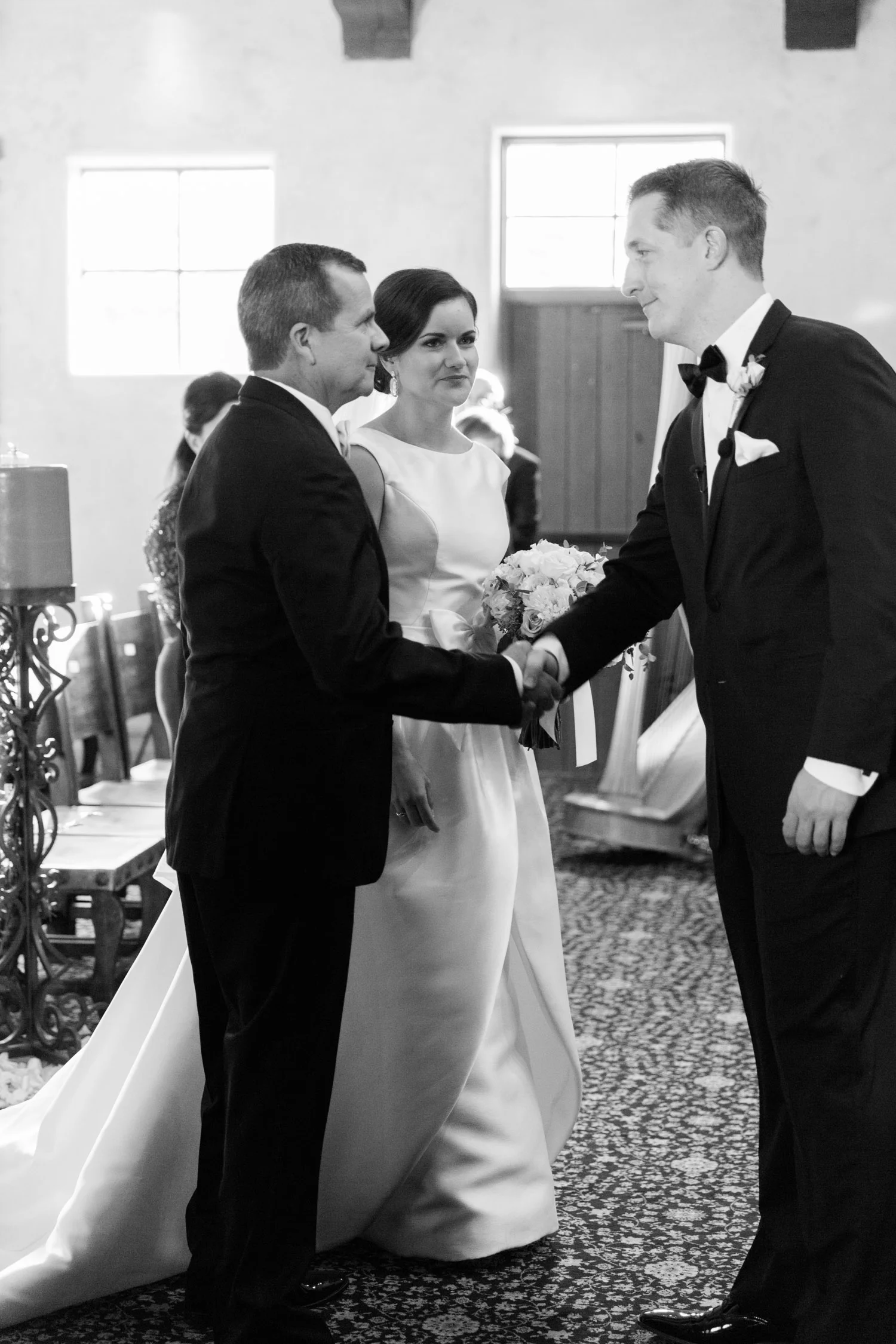 Groom shaking father of the bride's hand at the alter