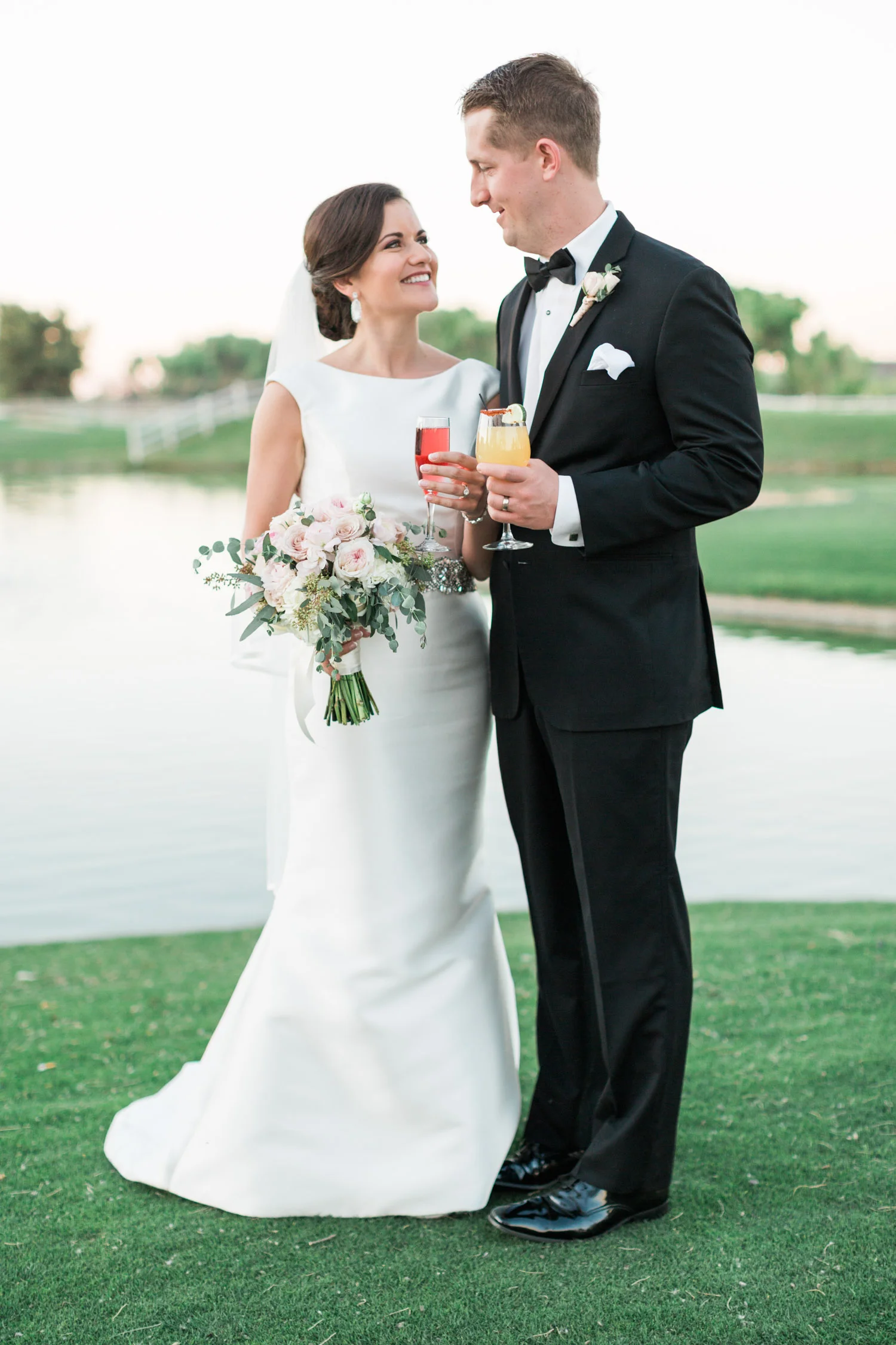 Couple cheersing with their signature wedding drinks in front of the lake at Tubac Golf Resort 