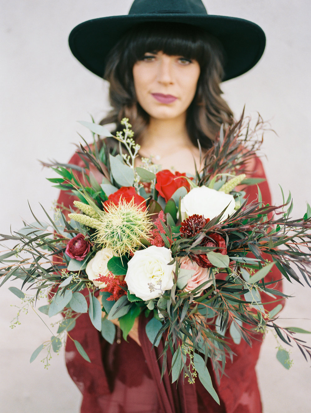  hipster bride wearing hat on her wedding day holding a desert bouquet&nbsp; 
