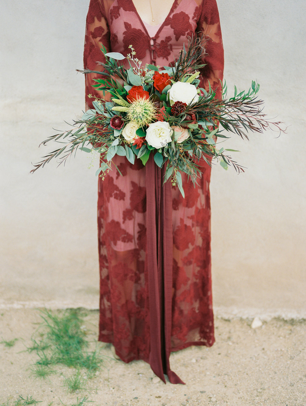  Bride in red burgundy lace dress holding desert fall bouquet with cactus 