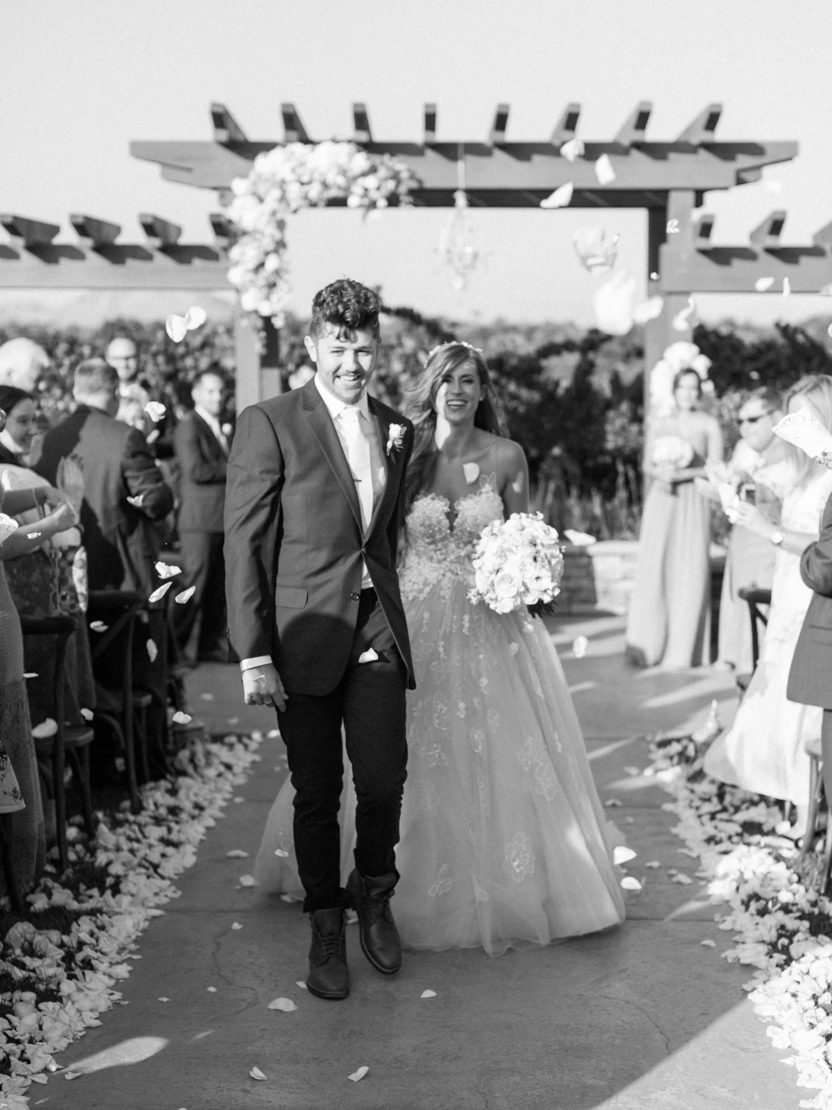 Bride & groom walking down the aisle, showered by flower petals! What a great exit. Harrison & Jocelyne's gorgeous Temecula wedding at Wiens Family Cellars captured by Betsy & John Photography