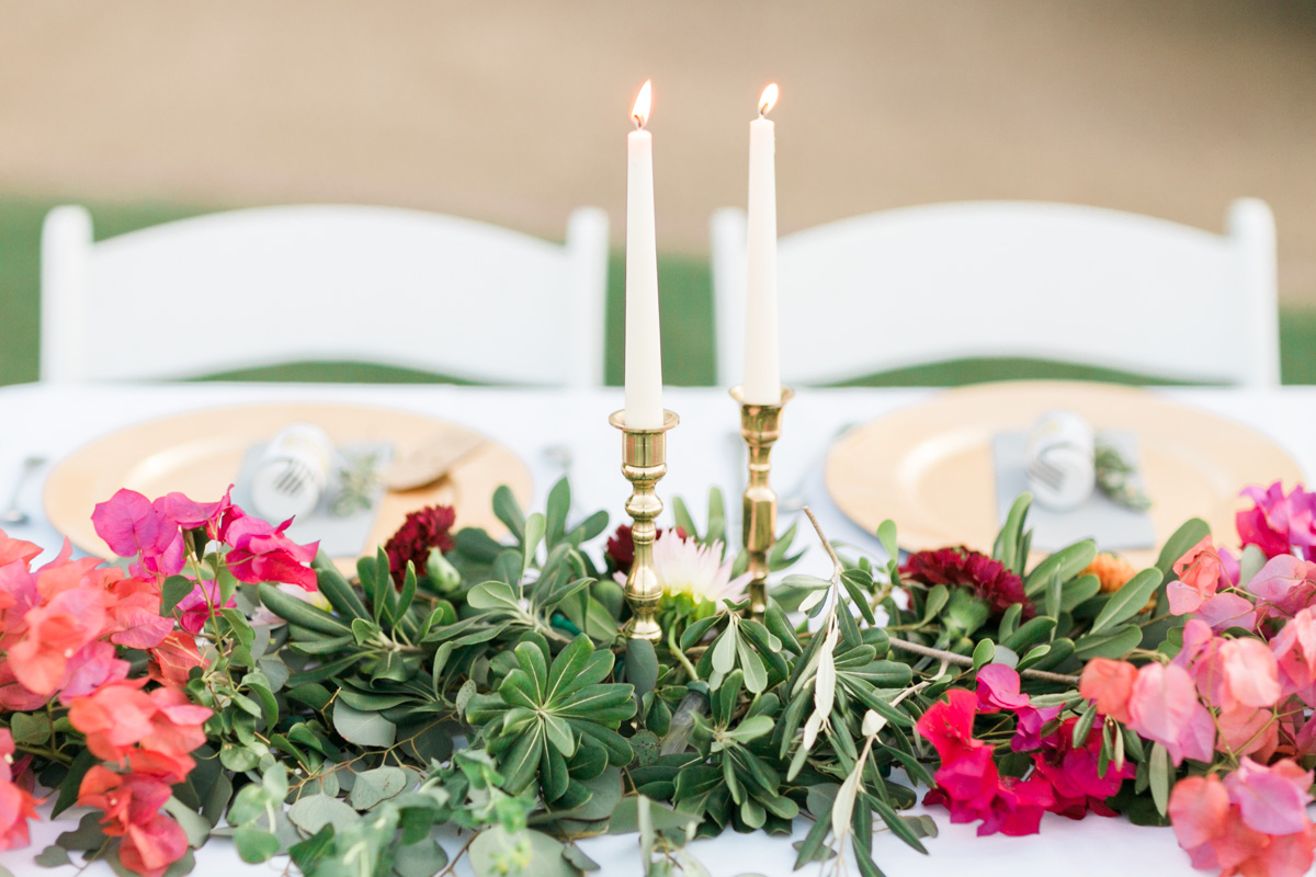 Brass candlesticks, greenery and bougainvillea on the head table 