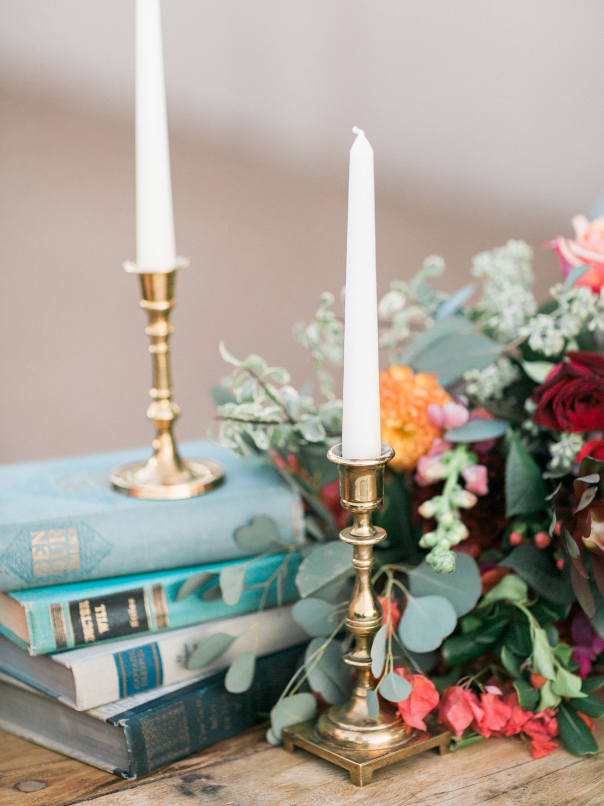 Charming wedding details, vintage books and brass candlesticks with draping greenery and florals 