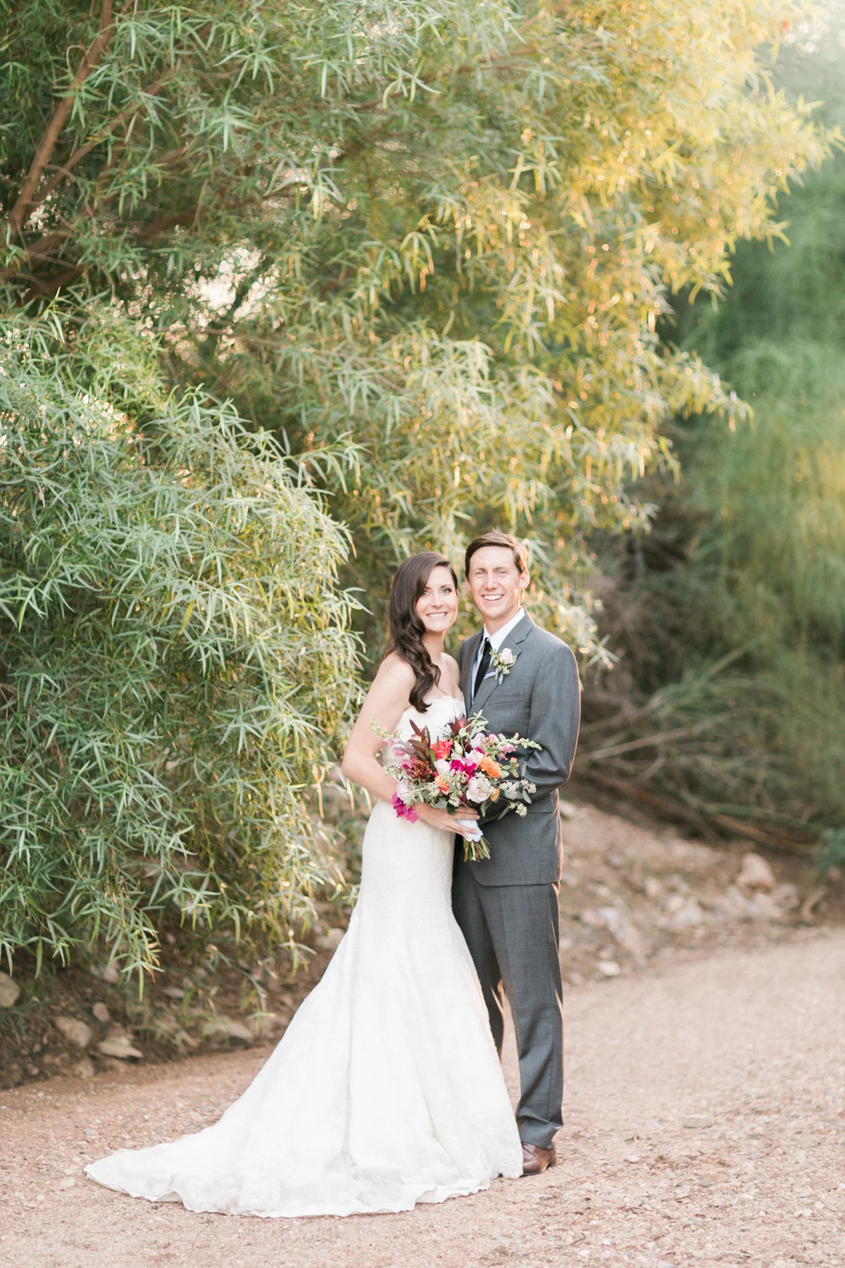 Bride and groom smiling at the camera with gorgeous golden light captured by Phoenix wedding photographers, Betsy & John 