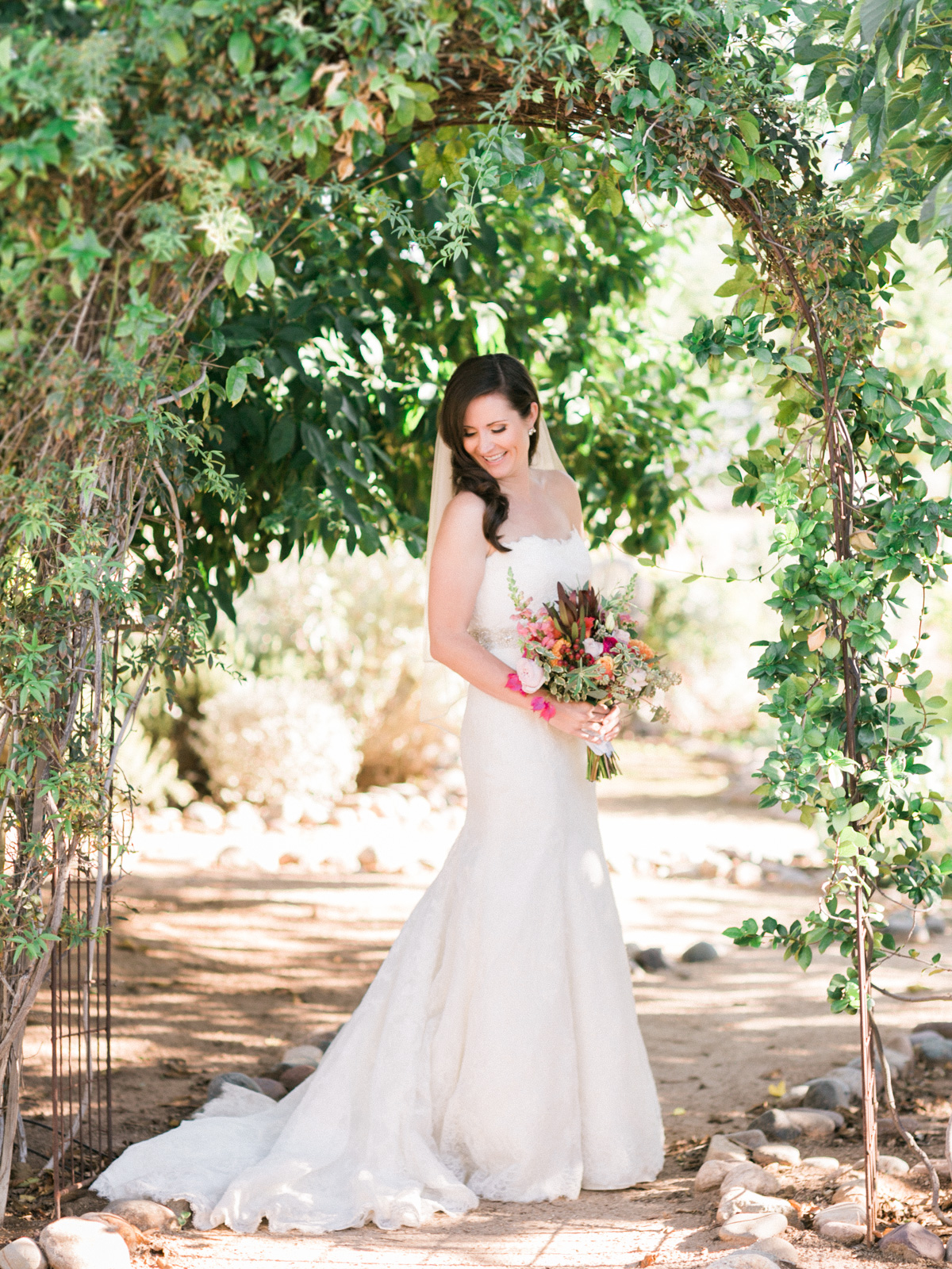 Gorgeous classic bride under green archway captured by Phoenix wedding photographers, Betsy & John 