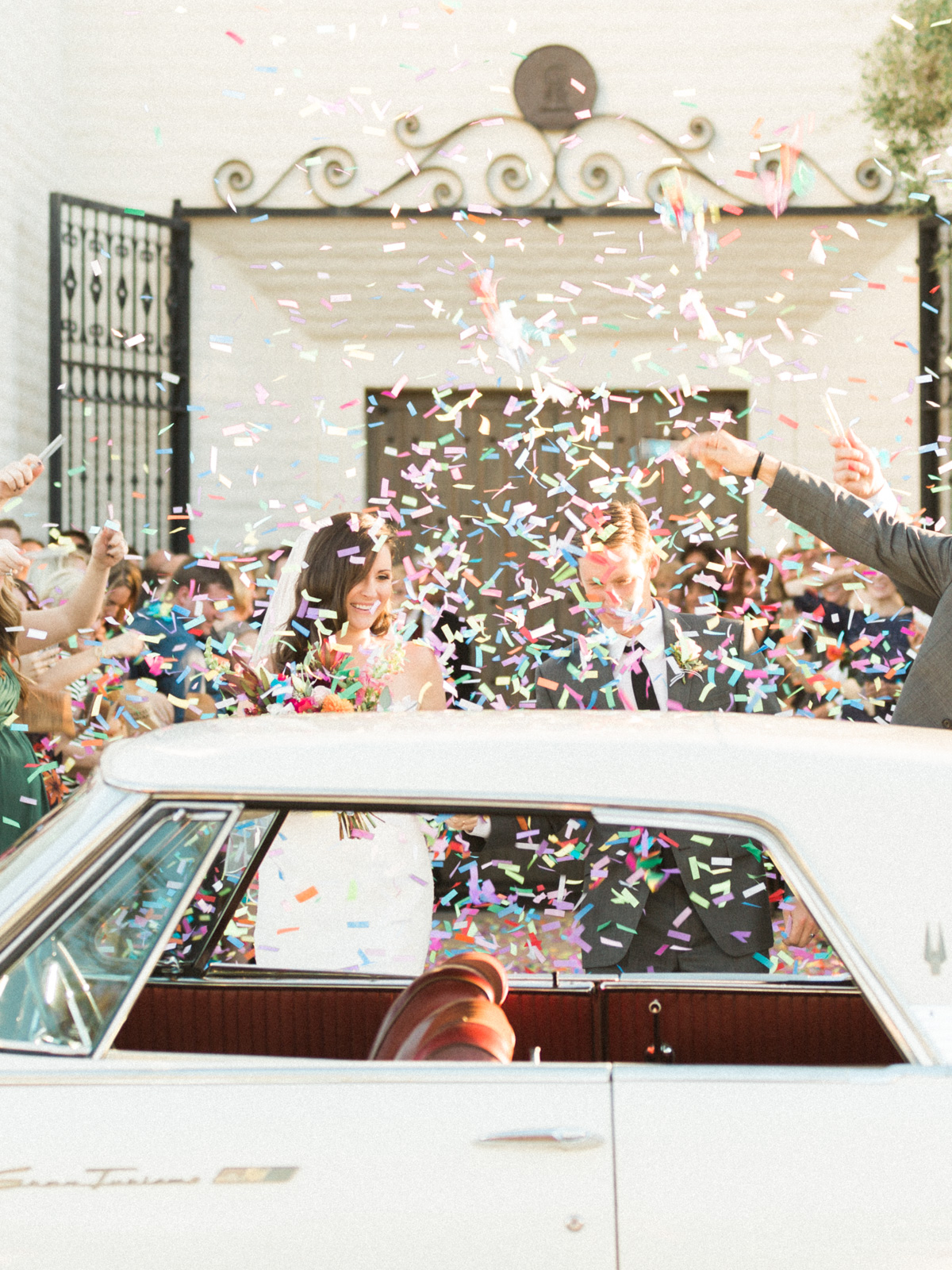 Confetti exit after ceremony, bride and groom getting into getaway car 