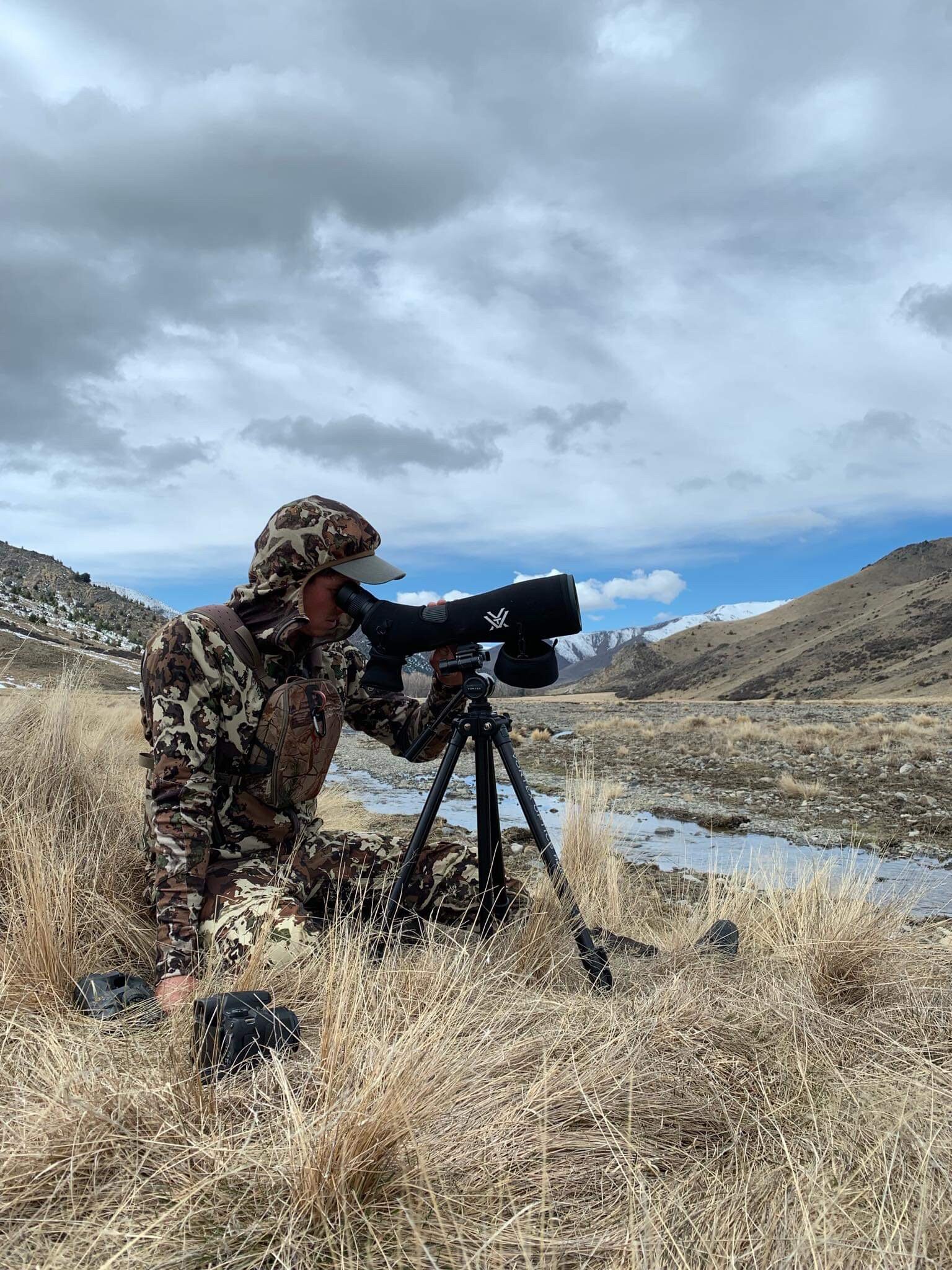 hunter wearing first lite clothing using a spotting scope