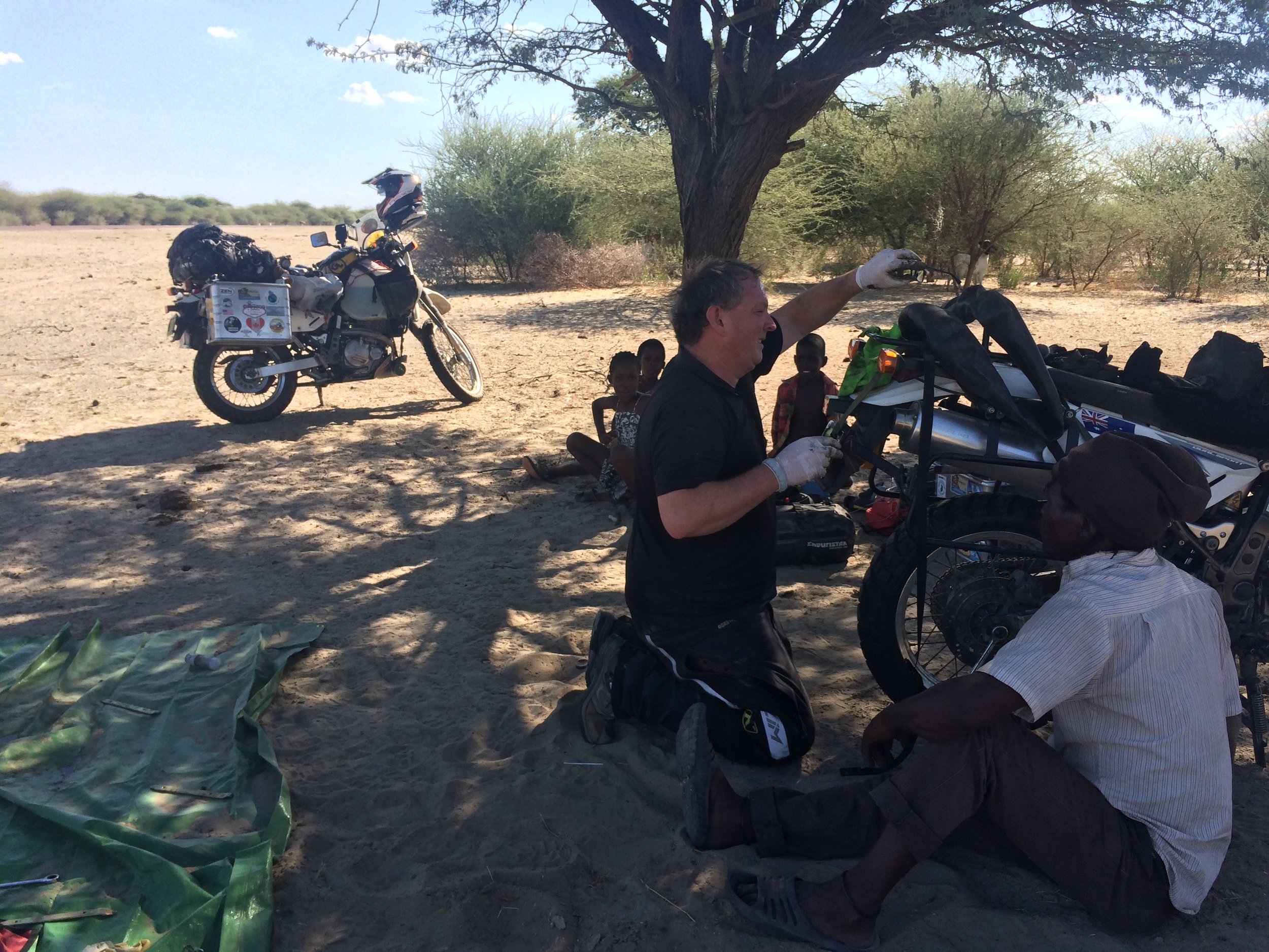 The bush mechanic helping put the wheel back on.