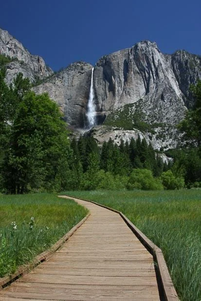 Wooden Track Winds Through Green Grass To Waterfall In Yosemite National Park