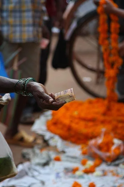 Old Indian Woman Extends Her Hand To Pay For Flowers In A Market