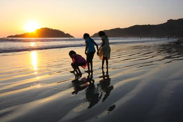 Three Young Girls Play By The Ocean At Sunset on Palolem Beach Goa India