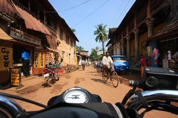 Royal Enfield Motorbike Riding Through Traditional Street Scene In Southern India