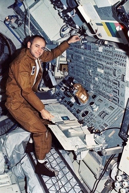 Compare the right-hand figure in painting 22 with Skylab astronaut Alan Bean in the weightless neutral body posture with cleat-in-grid foot restraint at the solar telescope console (NASA photo S74-5150).